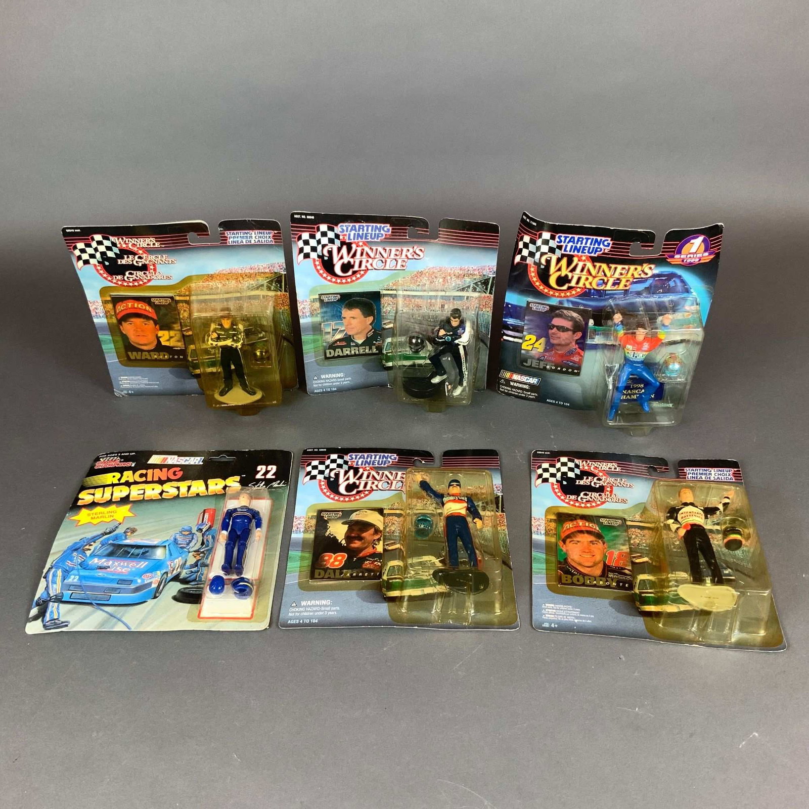 Assortment of Six Winners Circle and Racing Champions NASCAR Driver Action Figures: This collection features six vintage NASCAR driver action figures from the 1990s, each preserved in its original factory blister packaging. The group includes five figures from the Winner's Circle and