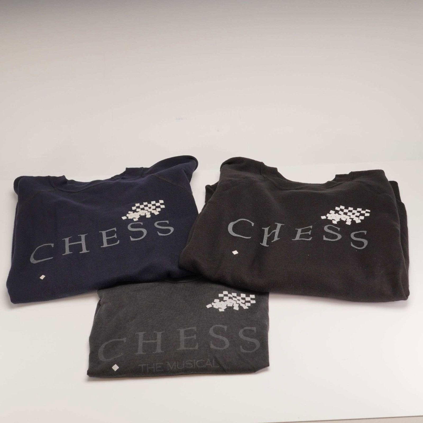 3pc Vintage 1980s Chess The Musical Apparel Items: This lot consists of three pieces of vintage promotional apparel for the 1980s stage production of Chess: The Musical, featuring music by Benny Andersson and Bjorn Ulvaeus with lyrics by Tim Rice. The