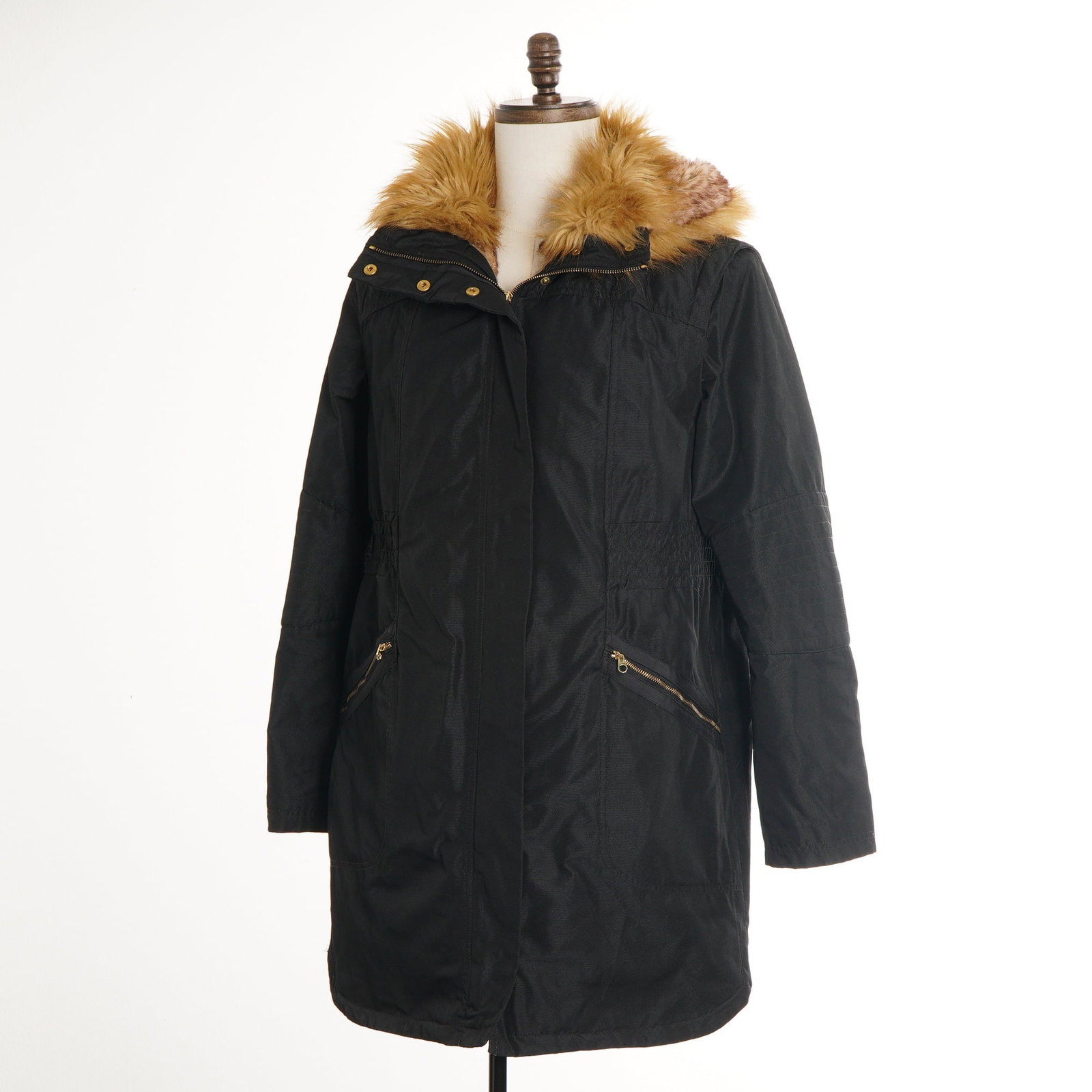Ted Baker London Black Parka Coat with Faux Fur Hood Size 4: A women's mid-length black parka coat by Ted Baker London. The garment features a synthetic exterior shell with an elasticized waist and tonal ribbed panels on the upper sleeves. It includes a large h