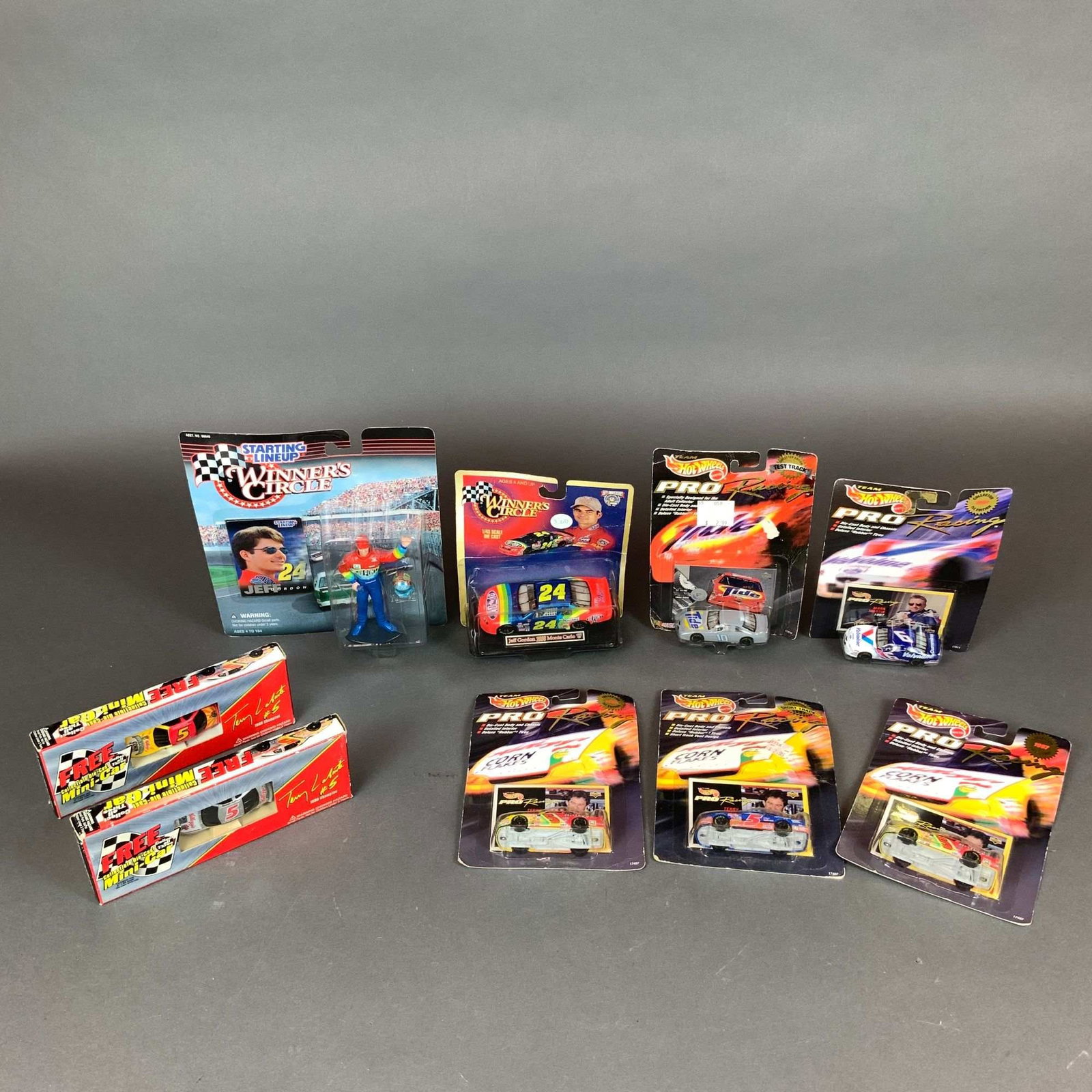 Nine Hot Wheels Pro Racing, Winners Circle & Mini-Cars NASCAR Model Cars & Collectibles: This collection includes nine NASCAR-themed die-cast cars and an action figure produced by manufacturers including Mattel under the Hot Wheels brand, Kenner, and Winner's Circle. The assortment featur