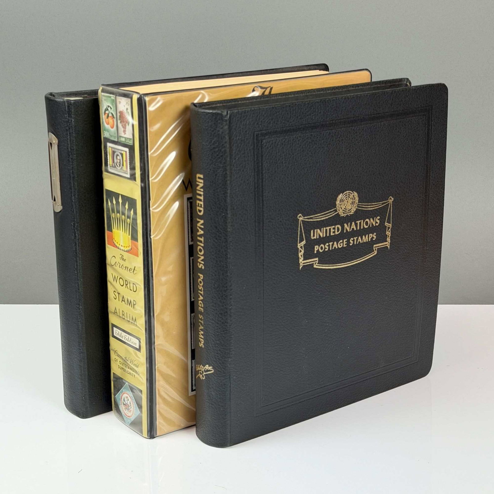 3pc UN, UK Channel Islands, and The Coronet World Postage Stamp Album Collection: This lot features three stamp books containing a diverse collection of global philatelic material. The primary volume is a black binder titled United Nations Postage Stamps, which contains a mix of