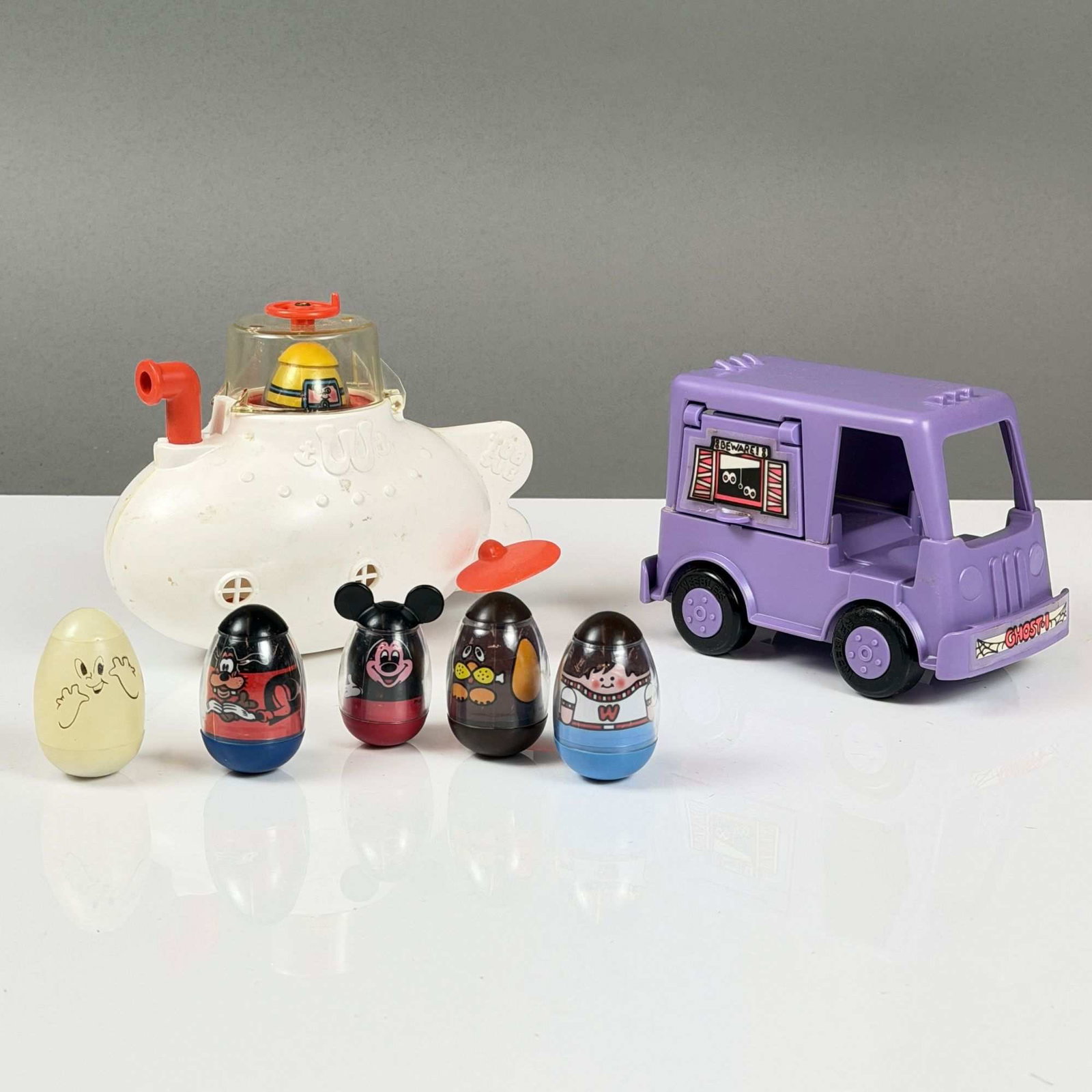 8pc Hasbro Weebles Toy Grouping: This 8pc Weeble Wooble grouping was manufactured by Hasbro and is dated 1977. The set is constructed of molded plastic and includes two vehicles and six weighted egg-shaped figures. The first vehicle