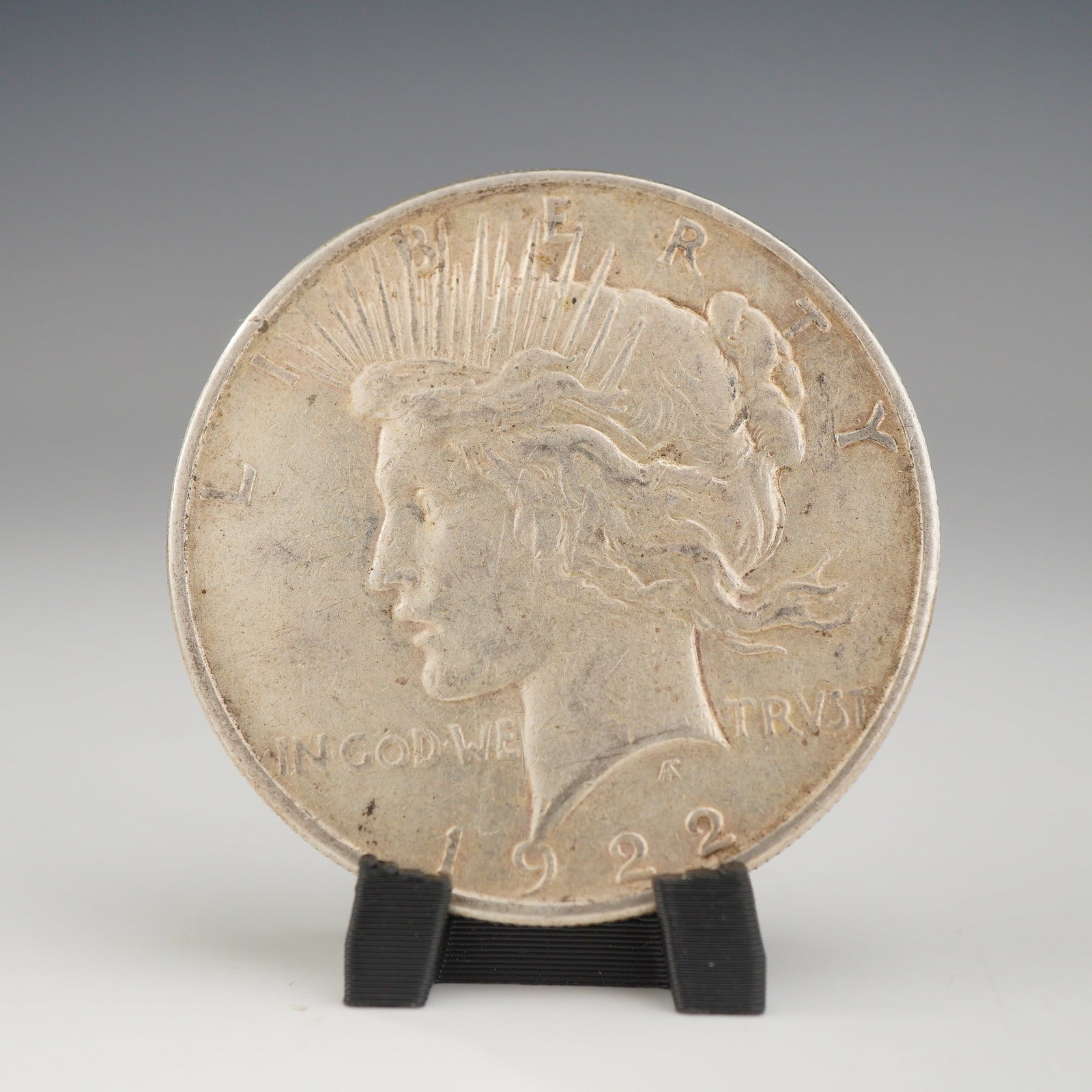 1922 US One Dollar Silver Peace Dollar Coin, Circulated: This lot features a 1922 US Peace silver dollar, struck at the Philadelphia Mint. The coin is composed of 90% silver and 10% copper. It features the standard Peace Dollar obverse and reverse designs b