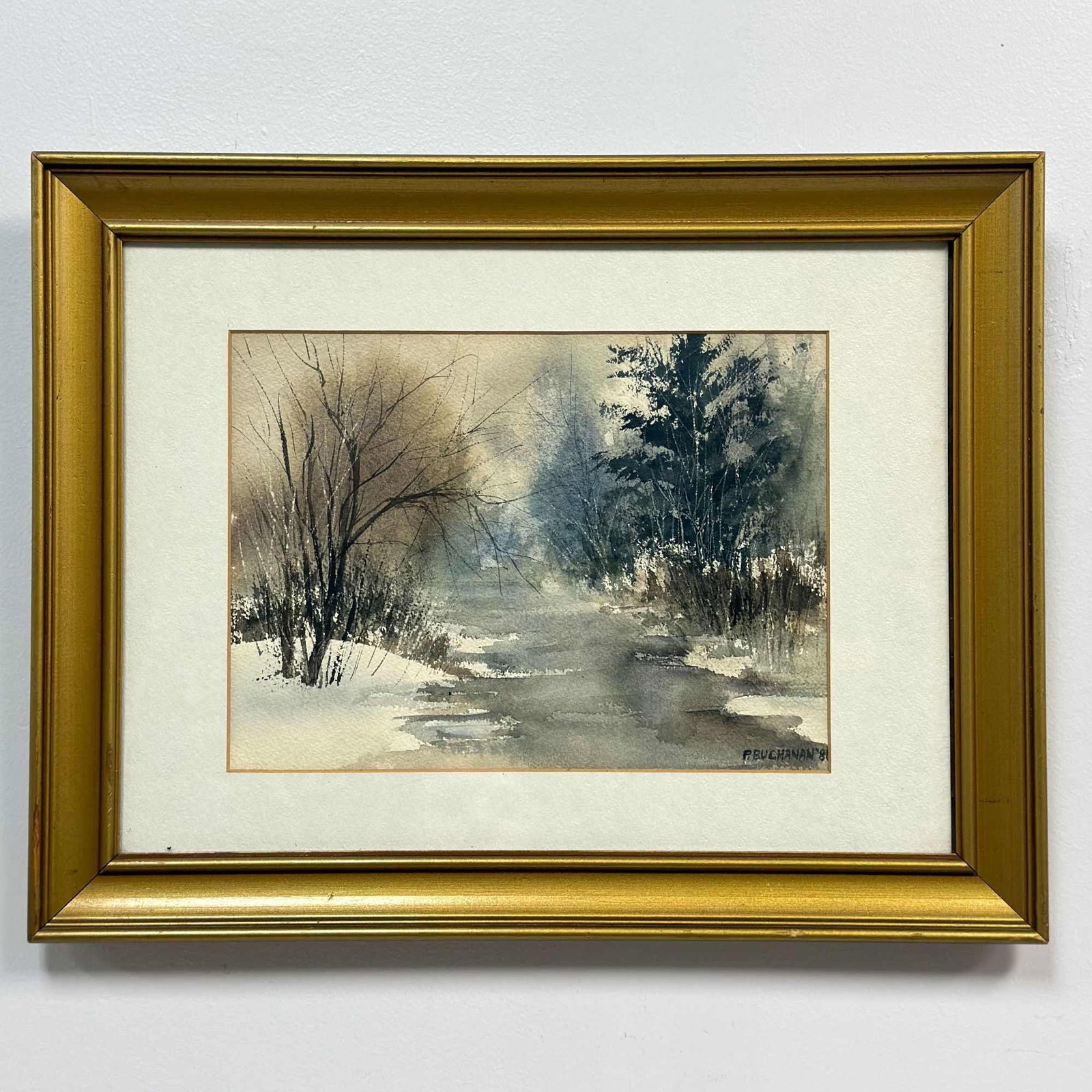 P. Buchanan (20th Century), Winter Stream Landscape, Original Watercolor Painting, 1981: This original watercolor painting on textured paper depicts an atmospheric winter landscape, featuring a winding stream set between snow-covered banks. The composition is flanked by bare deciduous tre