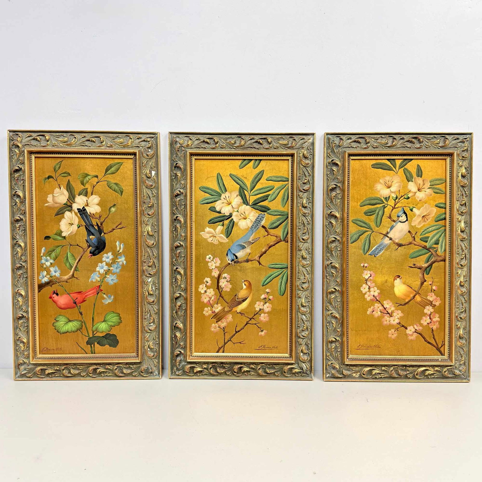 3pc Signed E. Garcia Mata, Chinoiserie Avian and Floral Studies: A trio of Chinoiserie-style oil paintings on gilded panels by E. Garcia Mata. The ornithological studies feature various songbirds, including cardinals, blue jays, and yellow finches, rendered in a na