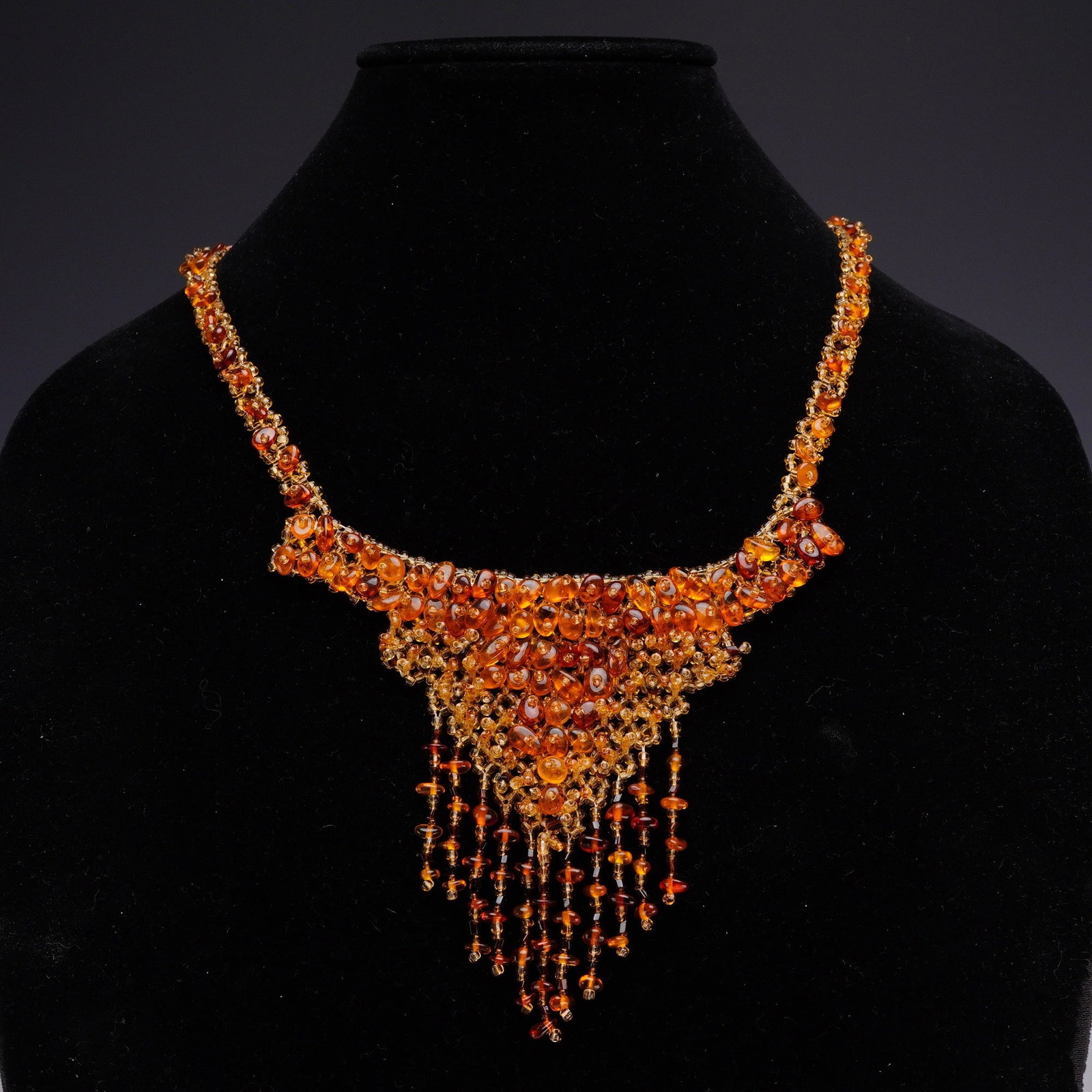 Handmade Russian Amber and Glass Seed Bead Statement Bib Necklace: This handmade Russian statement necklace is designed as a bib or collar with a decorative fringed drop. The piece is constructed from an intricate hand-woven mesh of amber-colored glass seed beads. Th