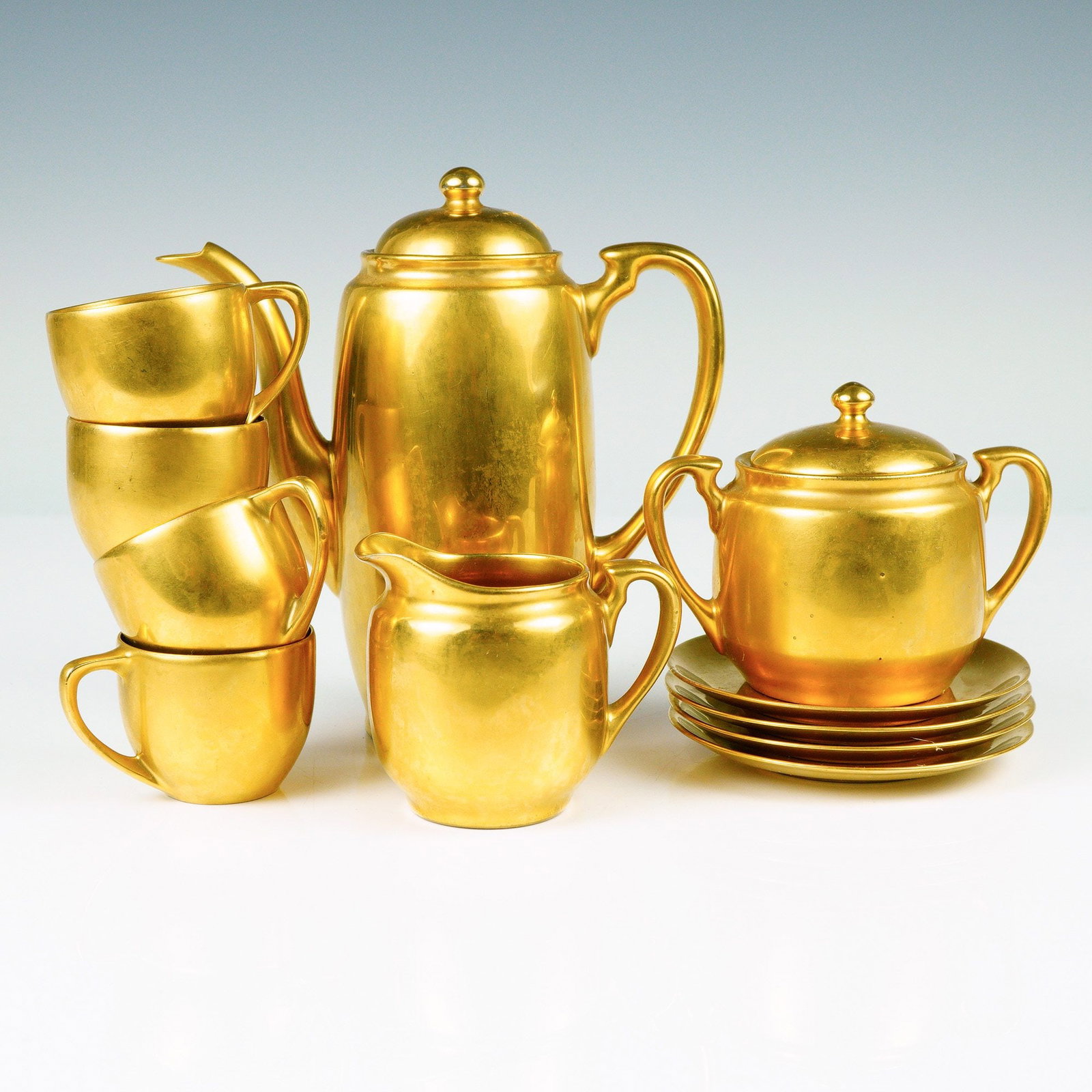 Gilded Porcelain Tea Service, Signed Sidney T. Callowhill: This striking Art Deco coffee and tea service set showcases the luxurious elegance of early 20th-century American ceramics. The ensemble features a rich golden luster glaze throughout, lending a bold,
