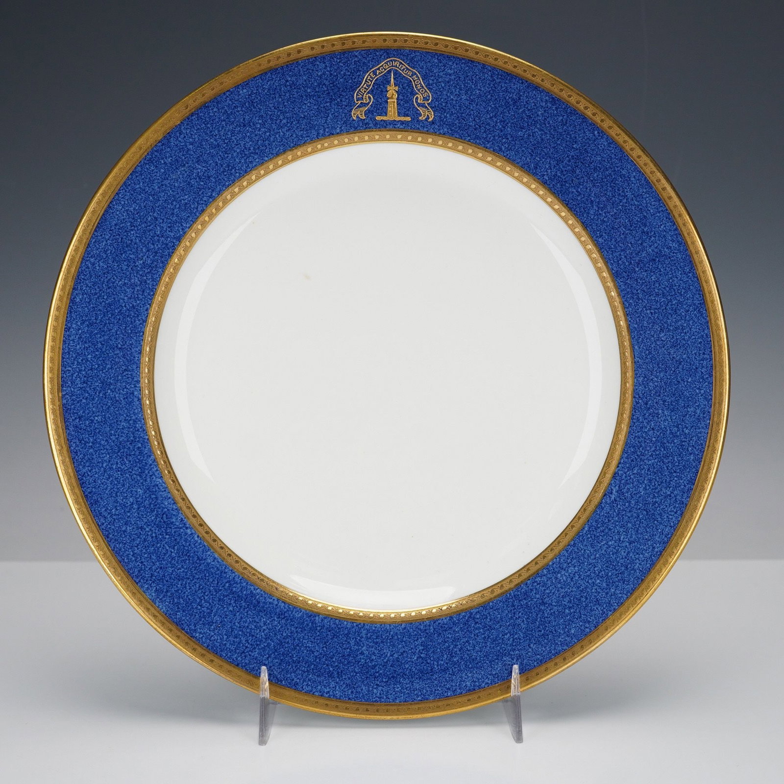 Wedgwood T. Goode Gilt and Cobalt Bone China Armorial Plate with Crest: A Wedgwood and T. Goode & Co. gilt and cobalt blue armorial plate crafted from fine bone china. This circular decorative plate features a wide, deep cobalt blue border with a finely textured or st