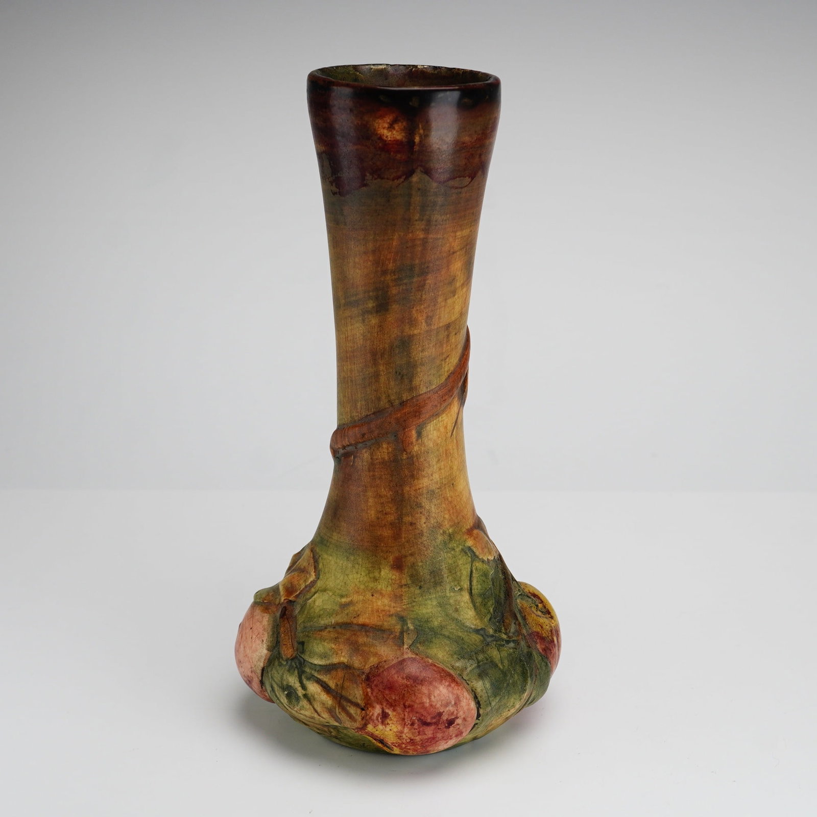 Weller Baldin Art Pottery Bud Vase with Molded Apple Tree Decoration, ca. 1920: A ceramic bud vase produced by Weller Pottery in the Baldin pattern, dating to approximately 1920. The vessel features a tall, slender neck that flares at the rim and transitions into a wide, bulbous 