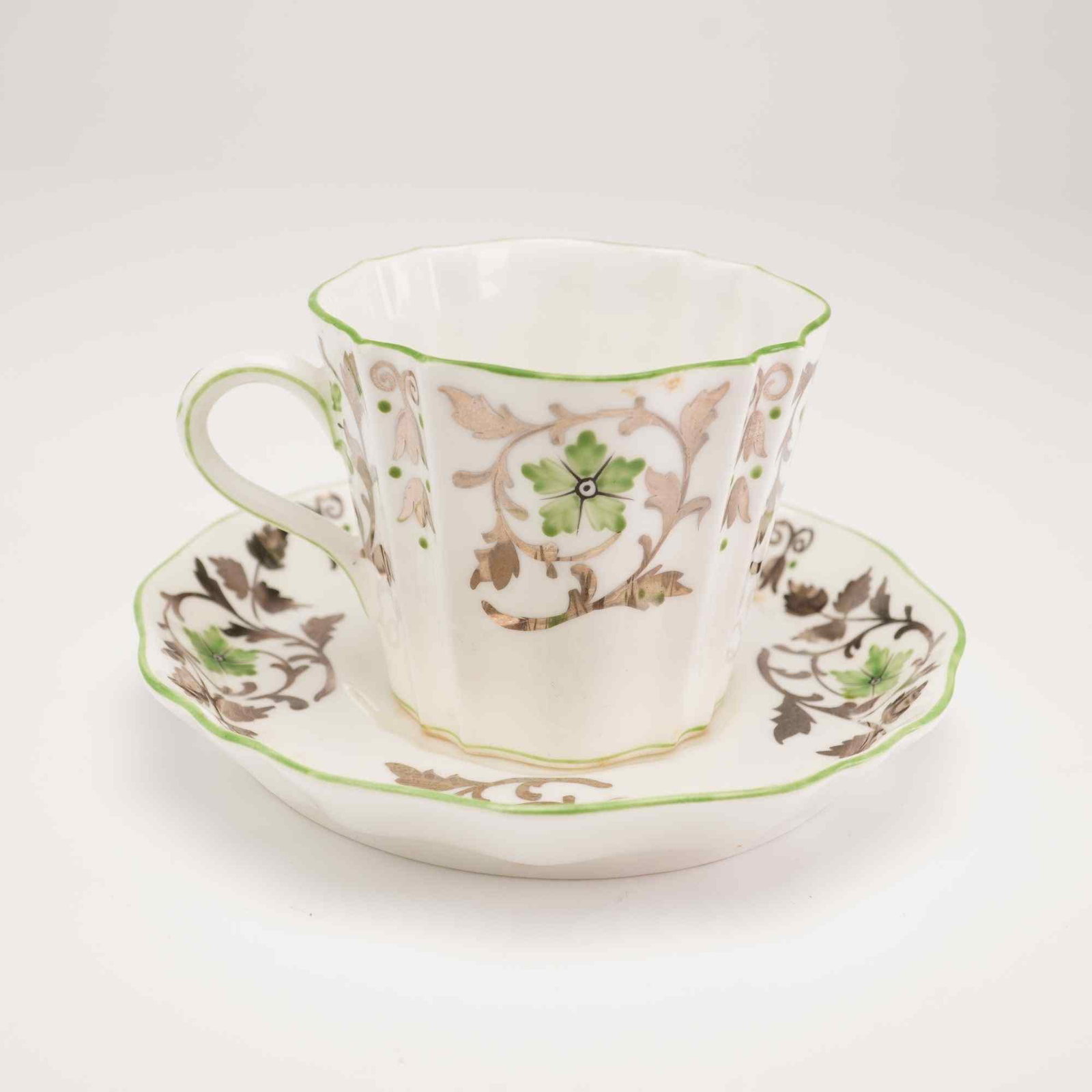 Wedgwood Bone China Teacup and Saucer, 1930: This Wedgwood fine bone china teacup and saucer set features a fluted, lobed form with scalloped rims. The decoration is composed of hand-colored transfer-printed elements, specifically a central