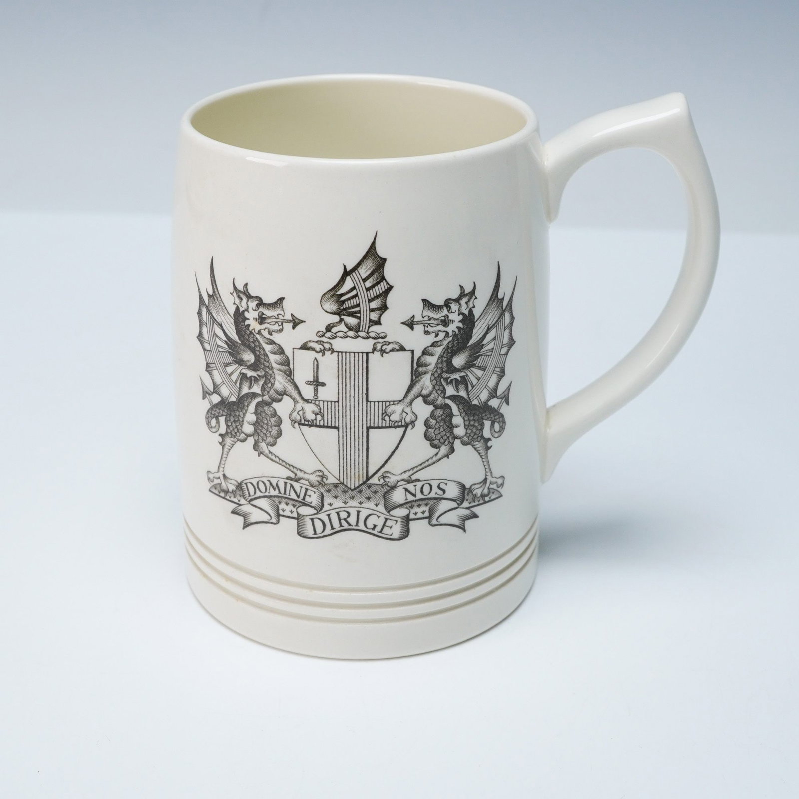 Wedgwood 'Arms of the City of London' Ceramic Tankard: A Wedgwood ceramic tankard featuring the 'Arms of the City of London.' The cream-colored, glazed ceramic body displays a monochrome heraldic crest on the front, comprising two winged, dragon-like