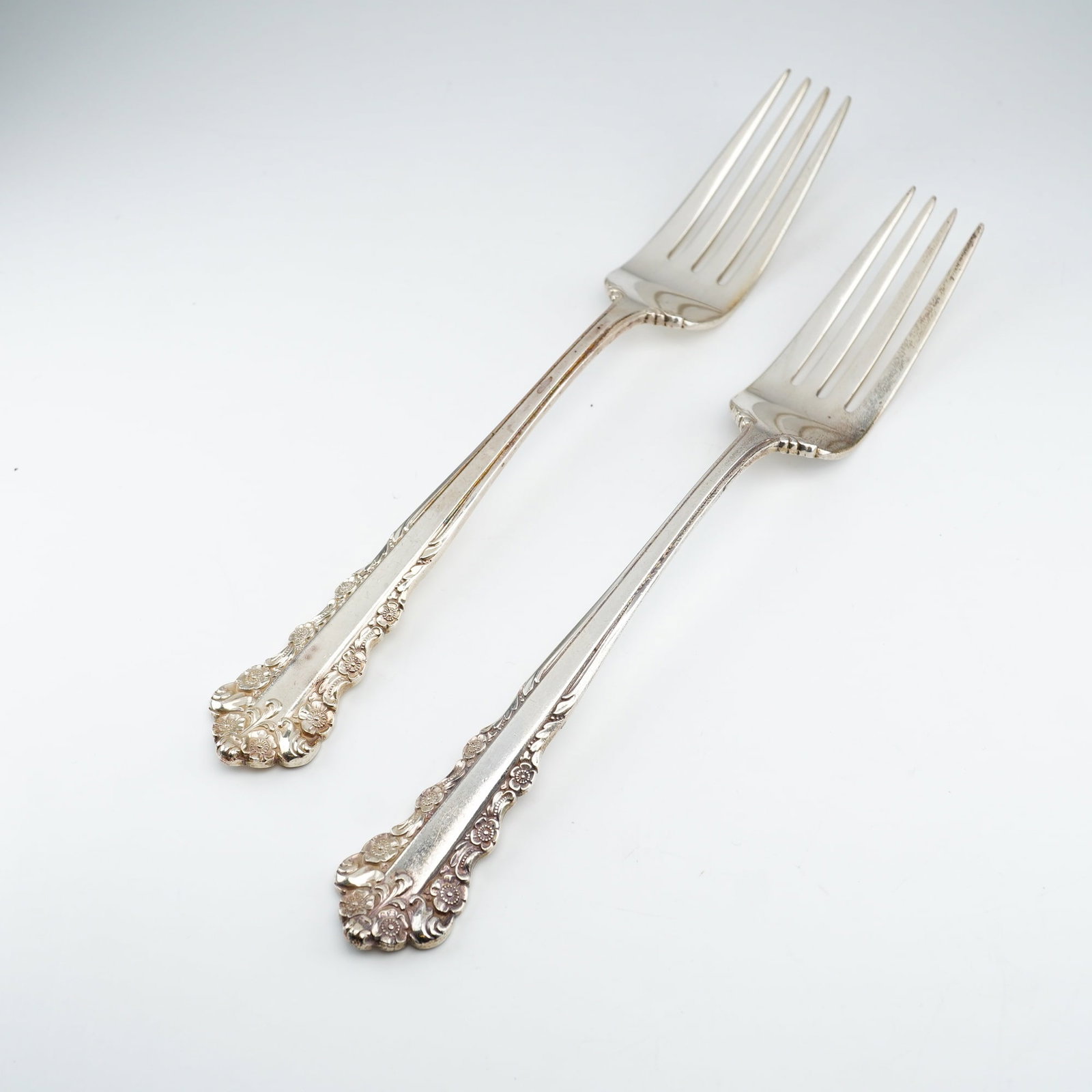 2pc Lunt Sterling Silver Dinner Forks, Belle Meade: Pair of sterling silver dinner forks in Lunt Silversmiths' "Belle Meade" pattern, known for its ornate Rococo-style aesthetic. The handles are embellished with raised floral decoration, scrolling acce