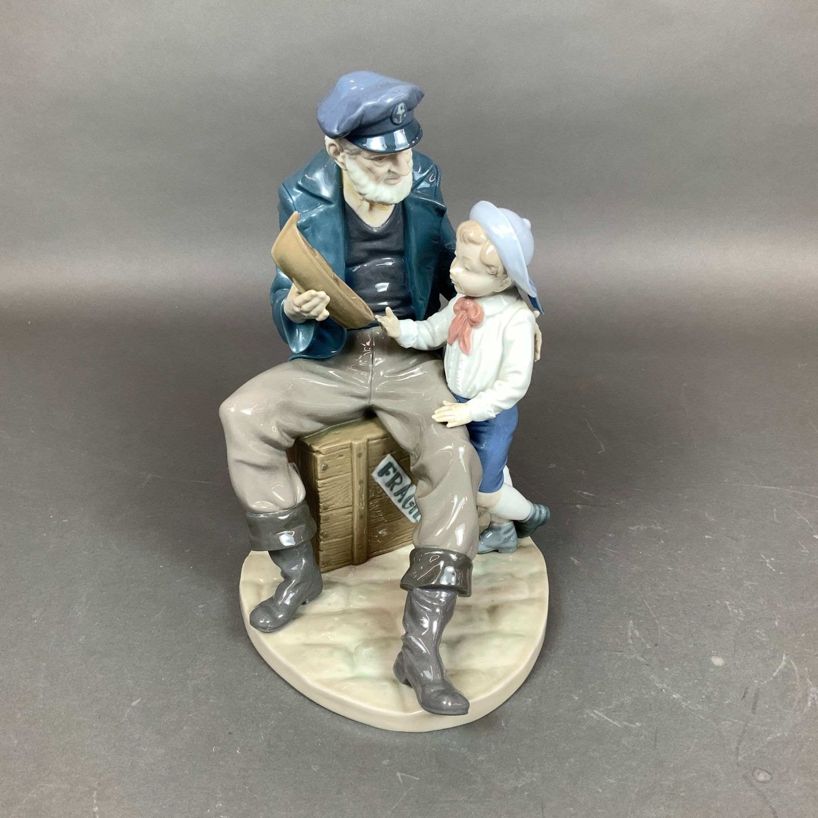 Lladro Porcelain Figurine, A Tall Yarn 01005207: A glazed porcelain figurine produced by the Spanish manufacturer Lladro, titled A Tall Yarn, also known as A Shorely Story or Sea Captain, model number 01005207. The sculpture depicts an elderly sailo