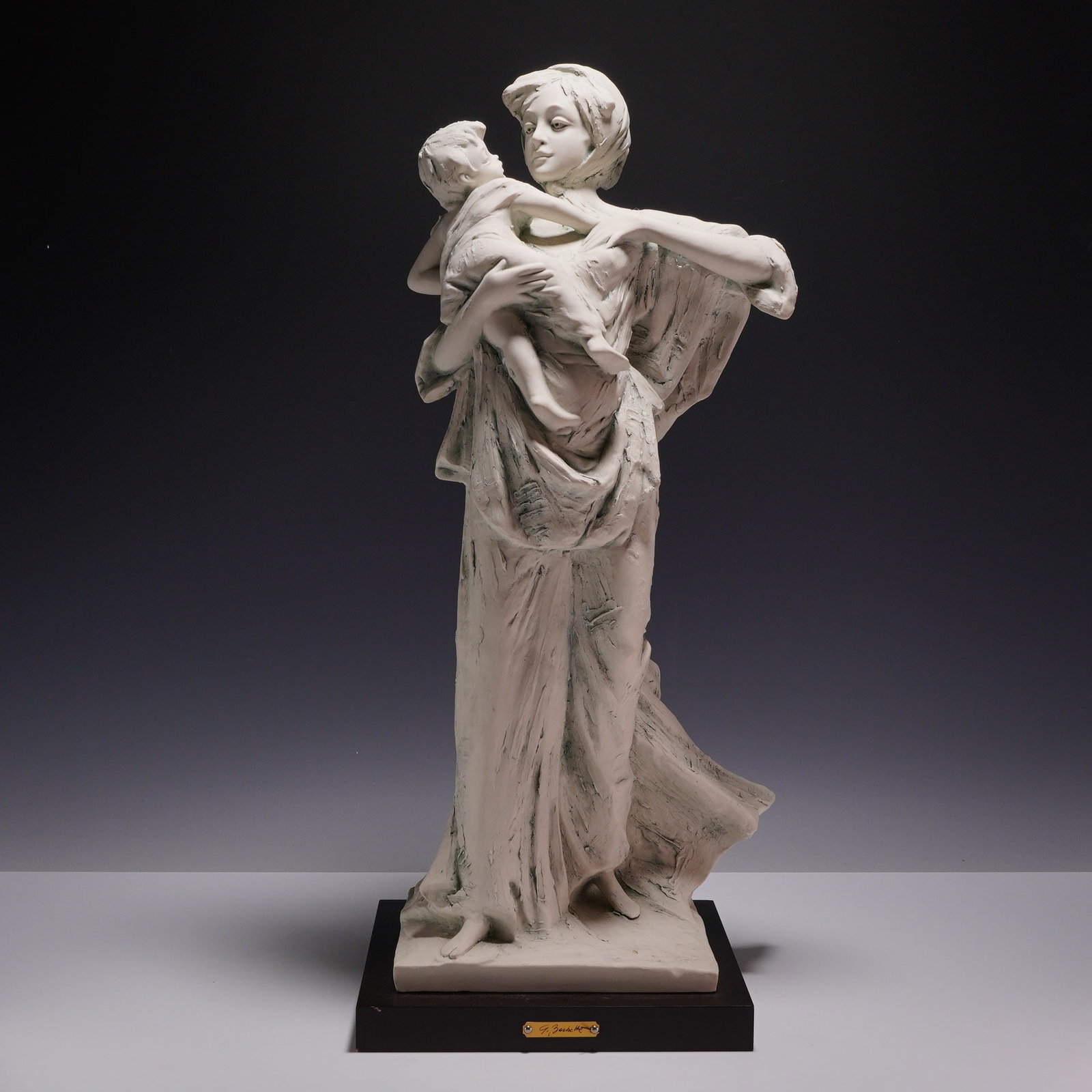 Giovanni Barbetta Italian Bisque Porcelain Mother and Child Sculpture: A Giovanni Barbetta limited edition sculpture of a mother and child. The piece is crafted from bisque-finished white porcelain with an intentional antiqued patination using gray-green tones in the rec