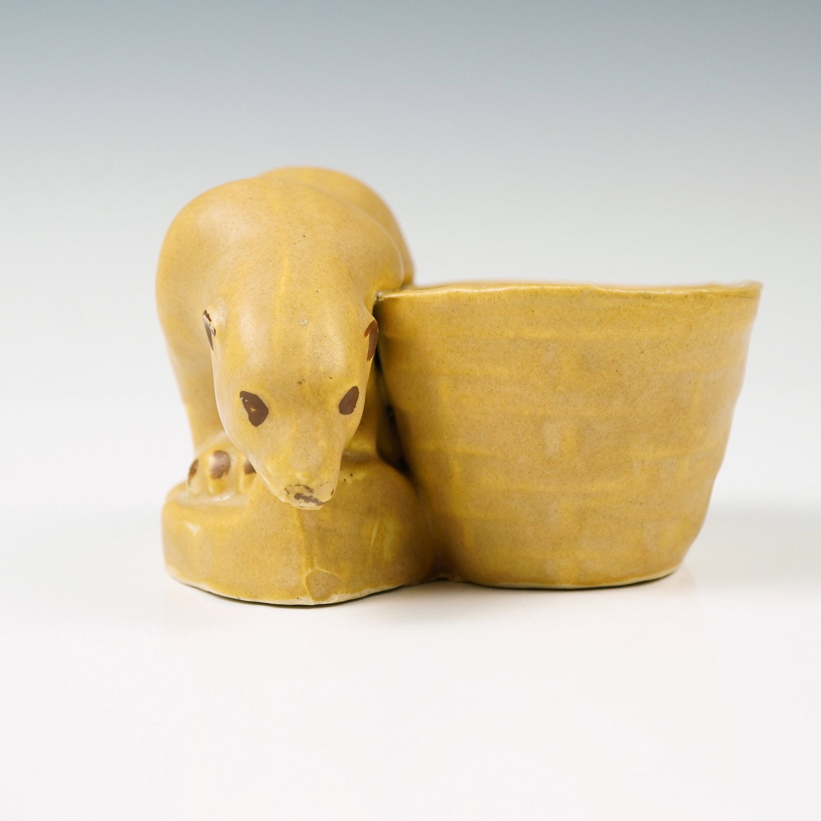 Niloak Yellow Polar Bear Planter: Striking mustard yellow planter featuring a bold sculpted polar bear crouched beside the bowl, with rich brown detailing on the eyes, ears, and paws. Niloak backstamp. Dimensions: 5.25"L x 4.5"W x