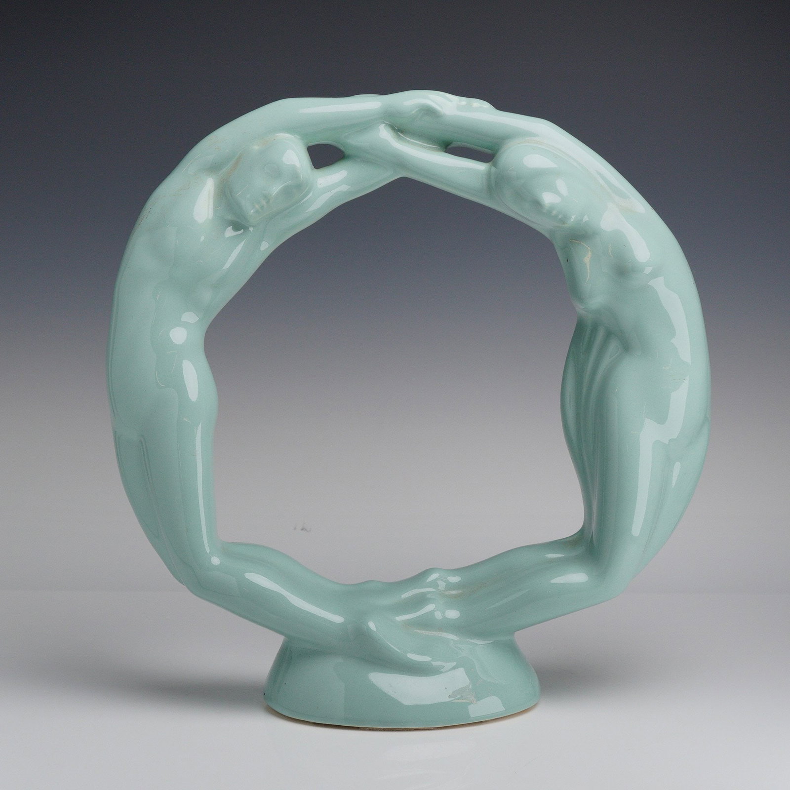 Royal Haeger Ceramic Sculpture, Circle of Love Eternity: This Art Deco-style piece features two stylized nude figures, one male and one female, joined at the hands and feet to form a continuous circular composition. The sculpture is finished in a uniform