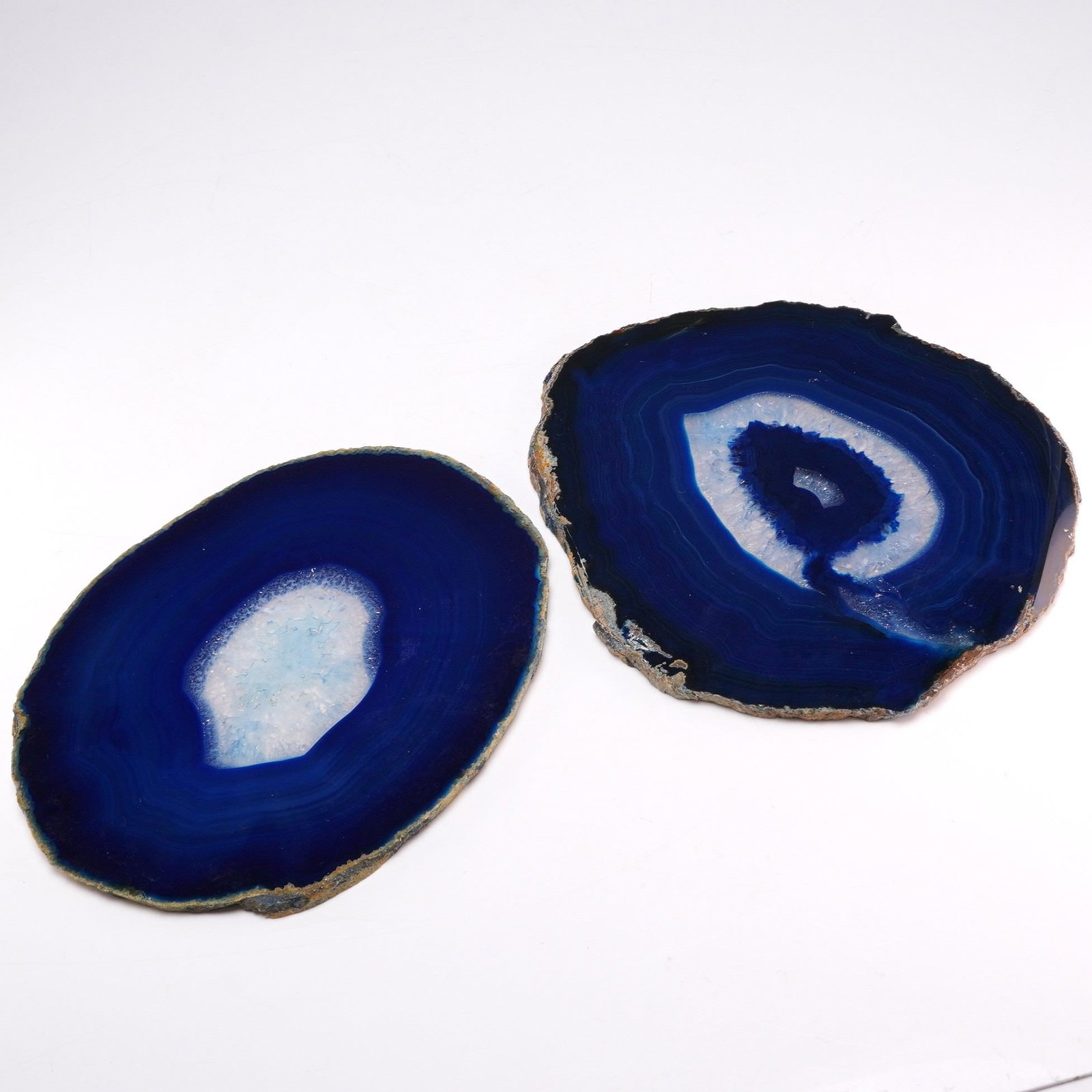 2pc Blue Agate Slices: This lot consists of two polished agate slices, dyed a deep cobalt blue to emphasize the natural concentric banding of the stone. Each specimen features a highly polished flat face revealing various