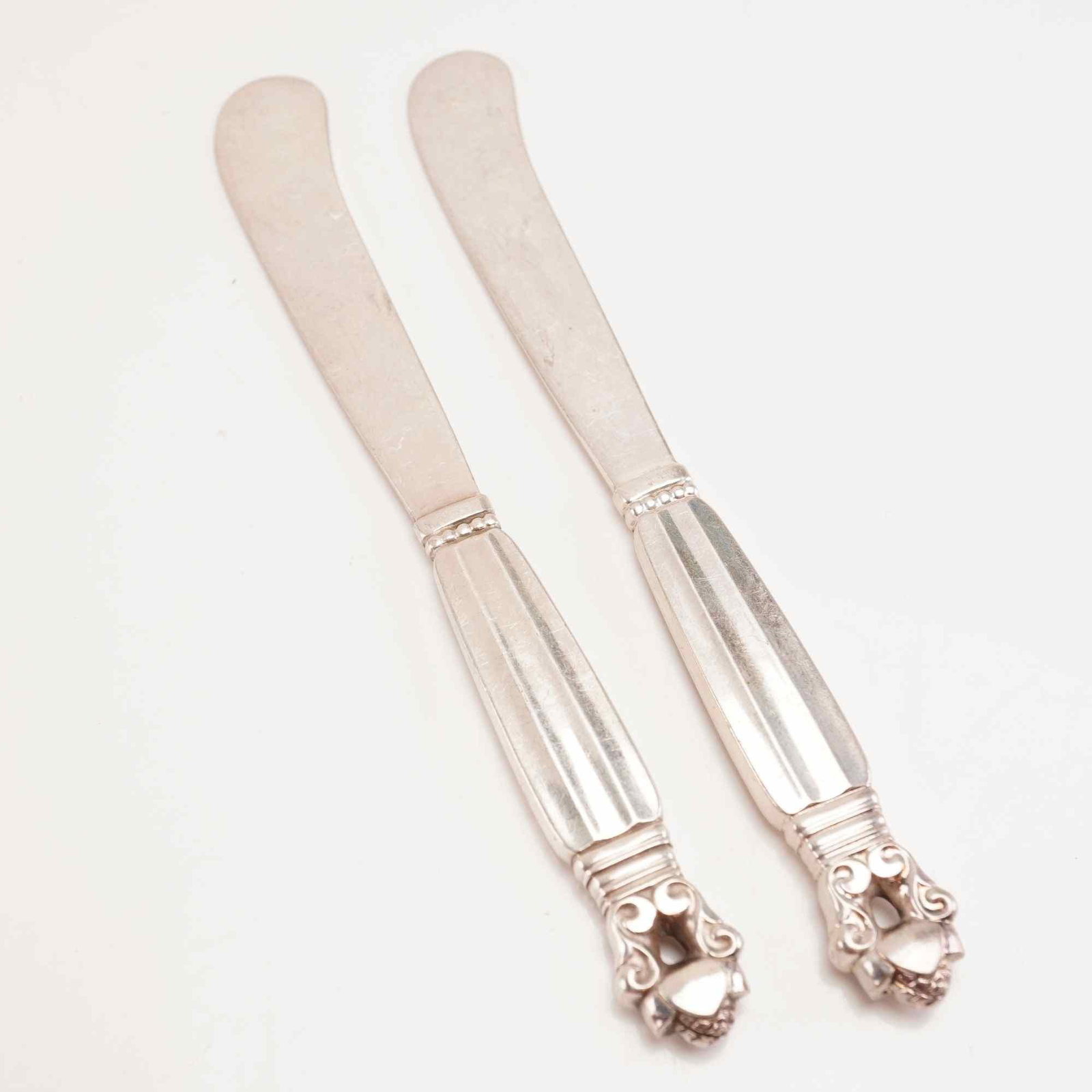 2pc George Jensen Sterling Silver Butter Spreaders, Acorn: Two Georg Jensen sterling silver butter spreaders, Acorn pattern. The design dates to 1915 and results from collaboration between Georg Jensen and designer Johan Rohde. Each spreader includes a sterli