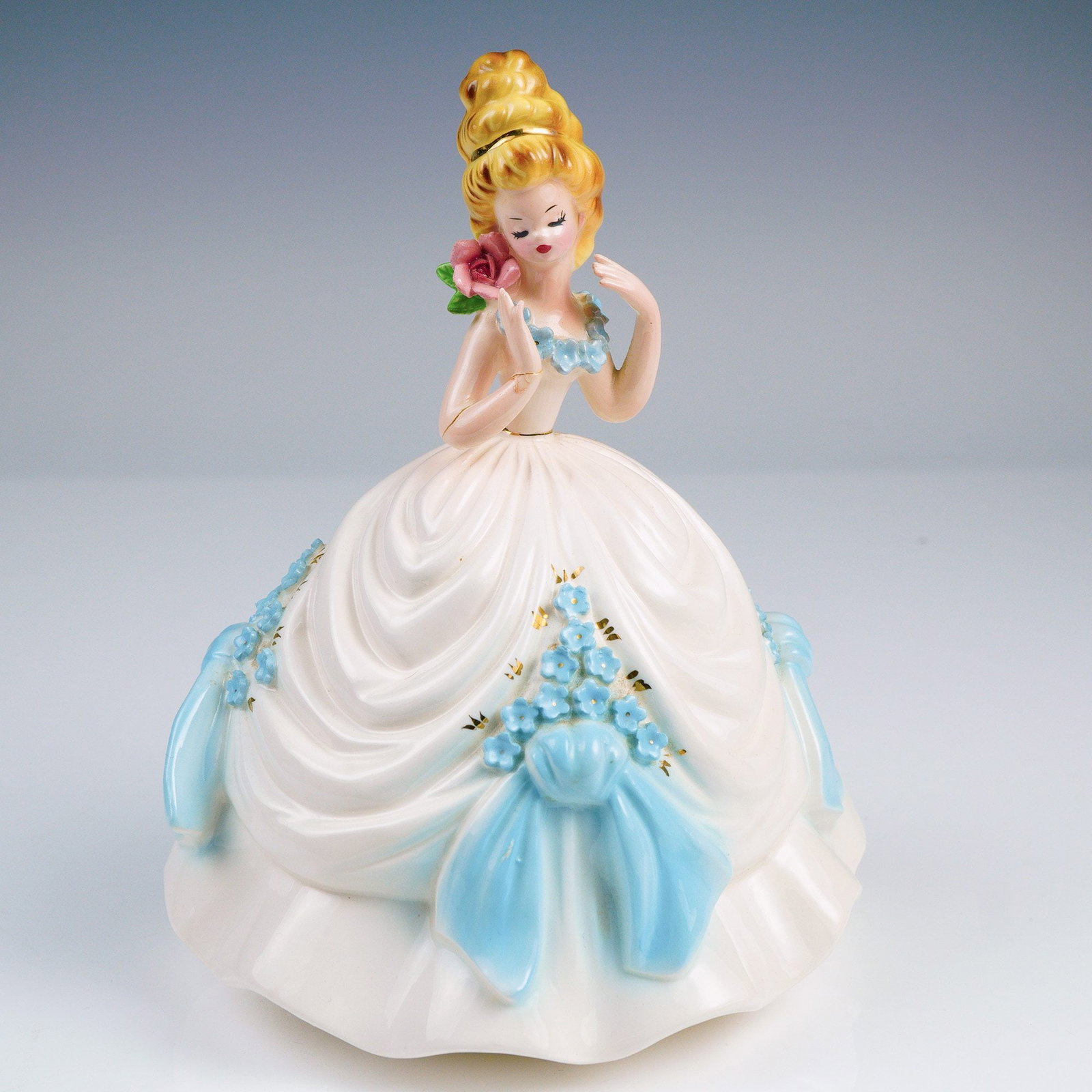 Originals Porcelain Figurine, Girl with Rose: This charming vintage porcelain figurine is a classic example of the beloved Josef Originals line, showcasing exquisite craftsmanship and timeless design. The figure depicts a young blonde girl dresse