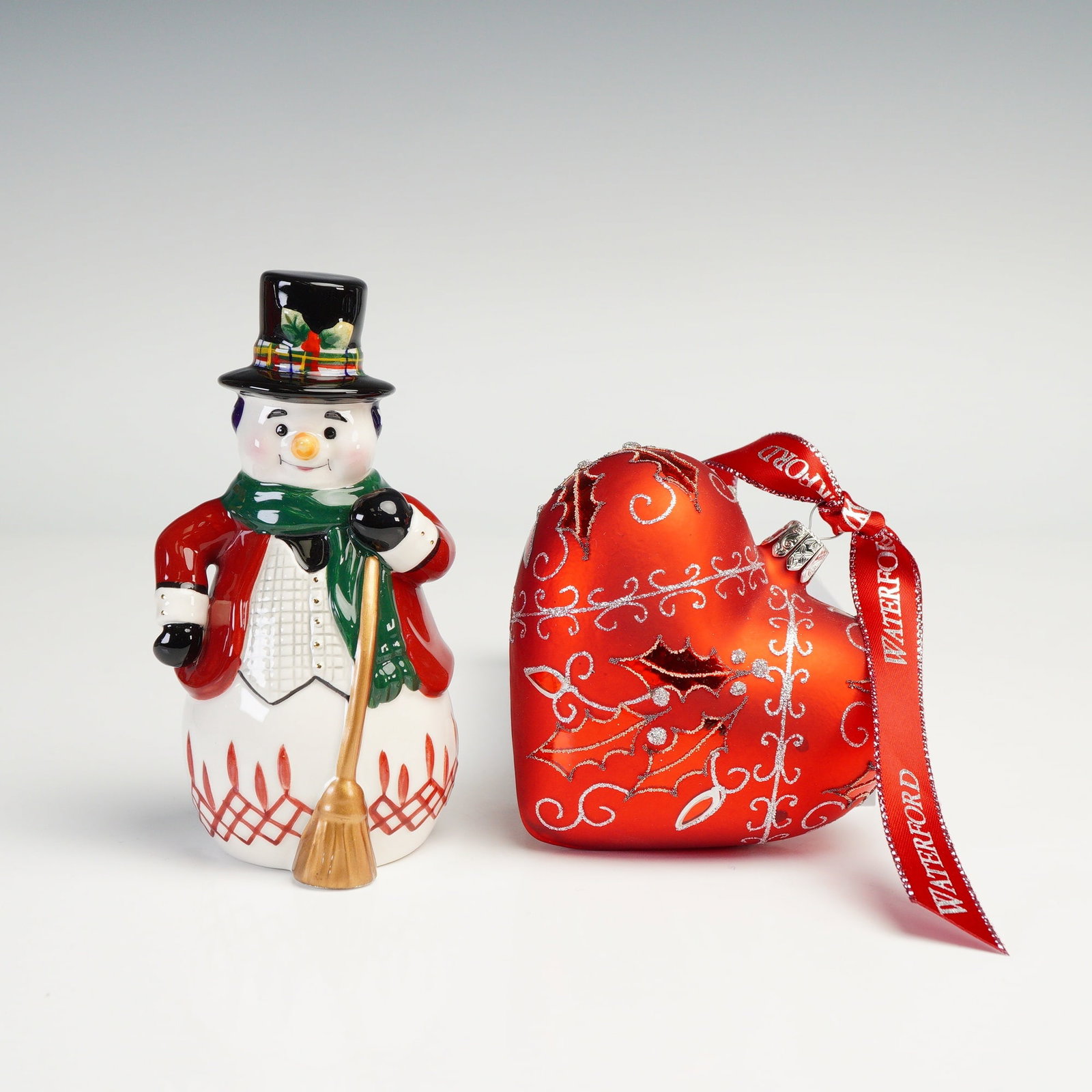 2pc Waterford Holiday Heirlooms Ornament and Bell, Holy Heart & Snowman: This Waterford Holiday Heirlooms set includes the Holly Heart glass ornament and the Jolly Plaid Snowman bell. The heart ornament features a rich red finish with glittered holly leaves, scroll accents