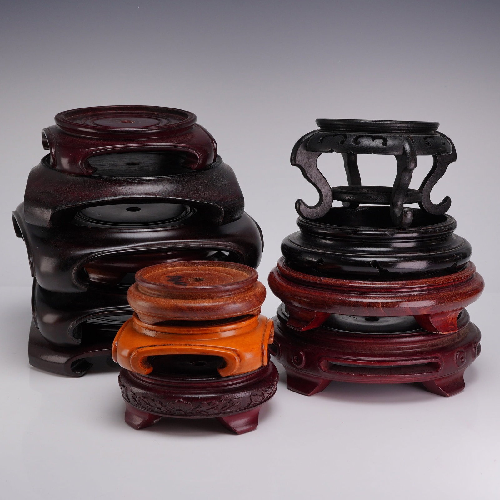 A Collection of 13 Wooden Chinese Display Bases: A collection of thirteen wooden Chinese display bases of various forms and finishes, designed for the support of vases, bowls, or lamps. The assortment includes four large lobed stands with a dark