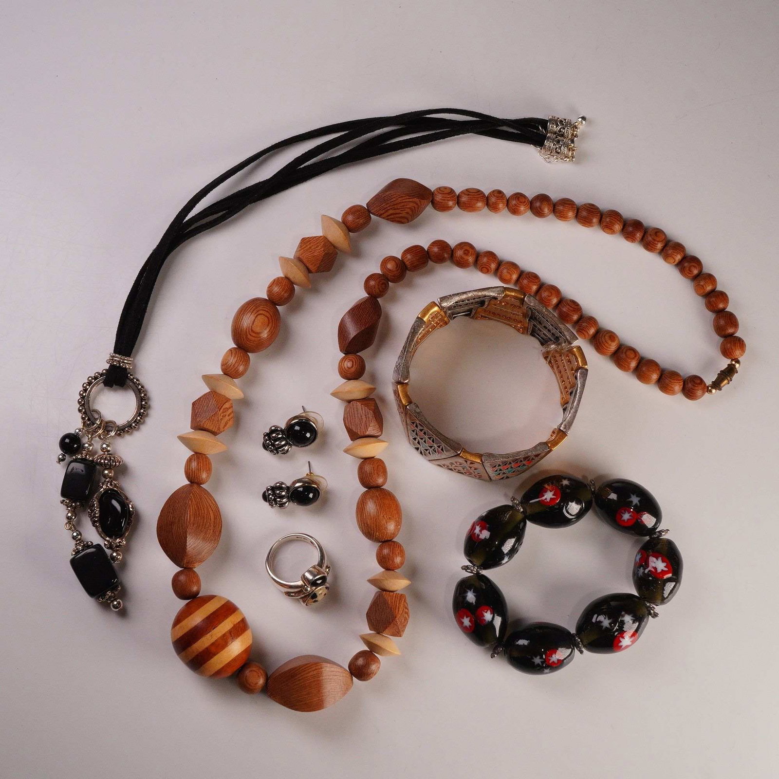 6pc Wood, Enamel, and Silver Tone Jewelry: A 6-piece lot totaling 7 items including a wood bead necklace, a black cord necklace with pendant, a sterling silver ring marked 925, a pair of black cabochon earrings, and two bracelets, one with