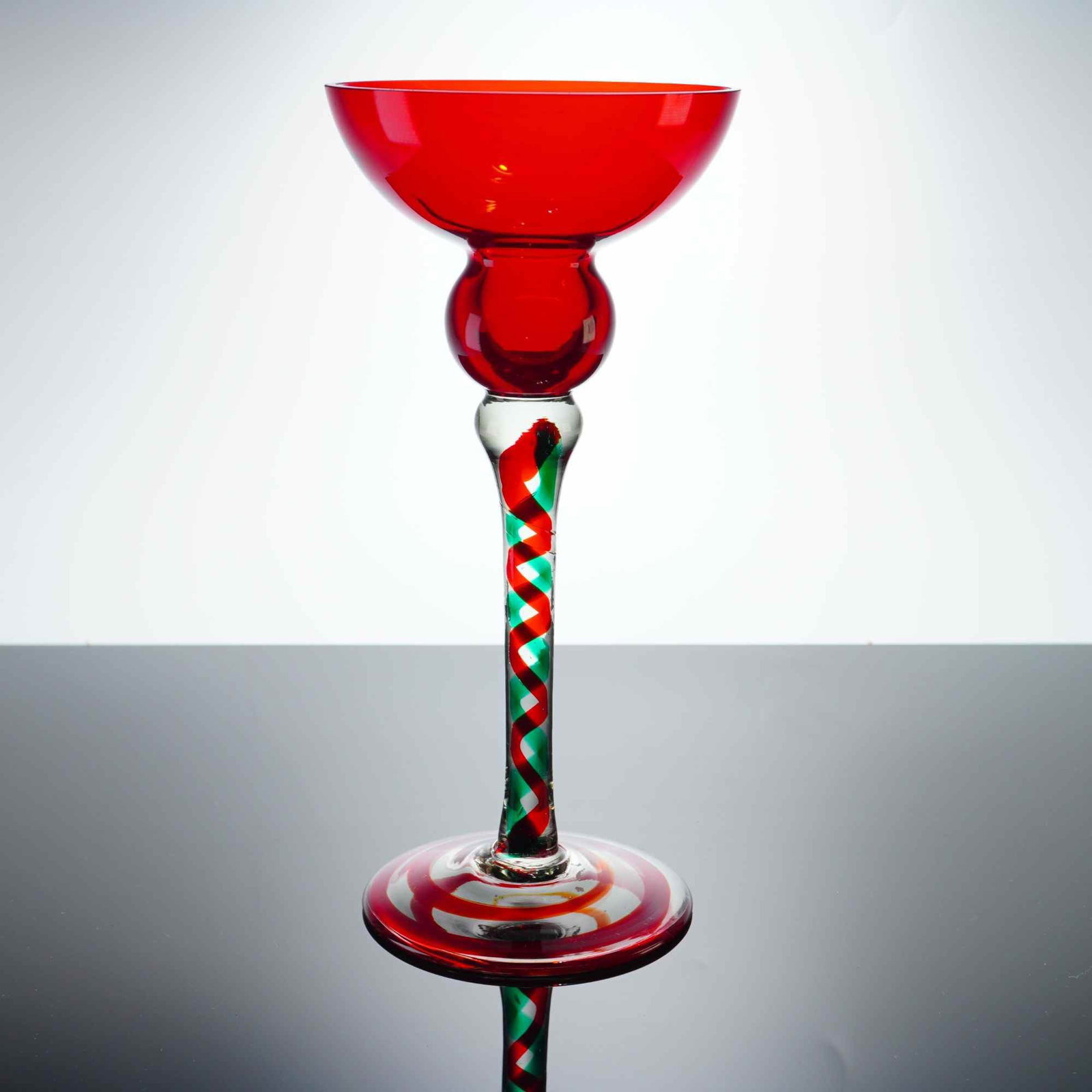 Polish Art Glass Red and Green Spiral Candlestick Holder: This large hand-blown Polish art glass candlestick holder features a wide, flared bobeche in a vibrant red color, supported by a matching red spherical knop. The clear glass stem contains an intricate