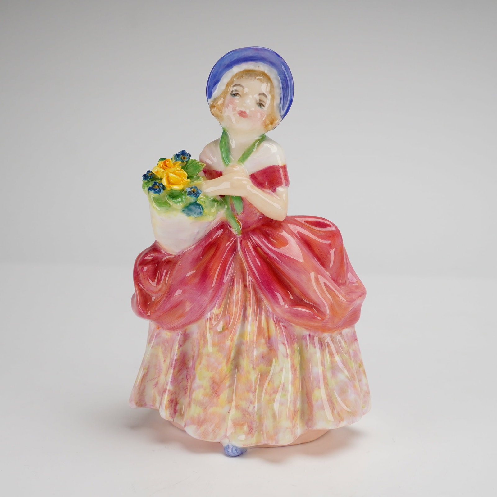 Royal Doulton Cissie Figurine HN1809: A Royal Doulton bone china figurine titled Cissie, model number HN 1809, designed by Leslie Harradine. The figure depicts a young girl in mid-20th-century style attire, wearing a wide-brimmed blue hat