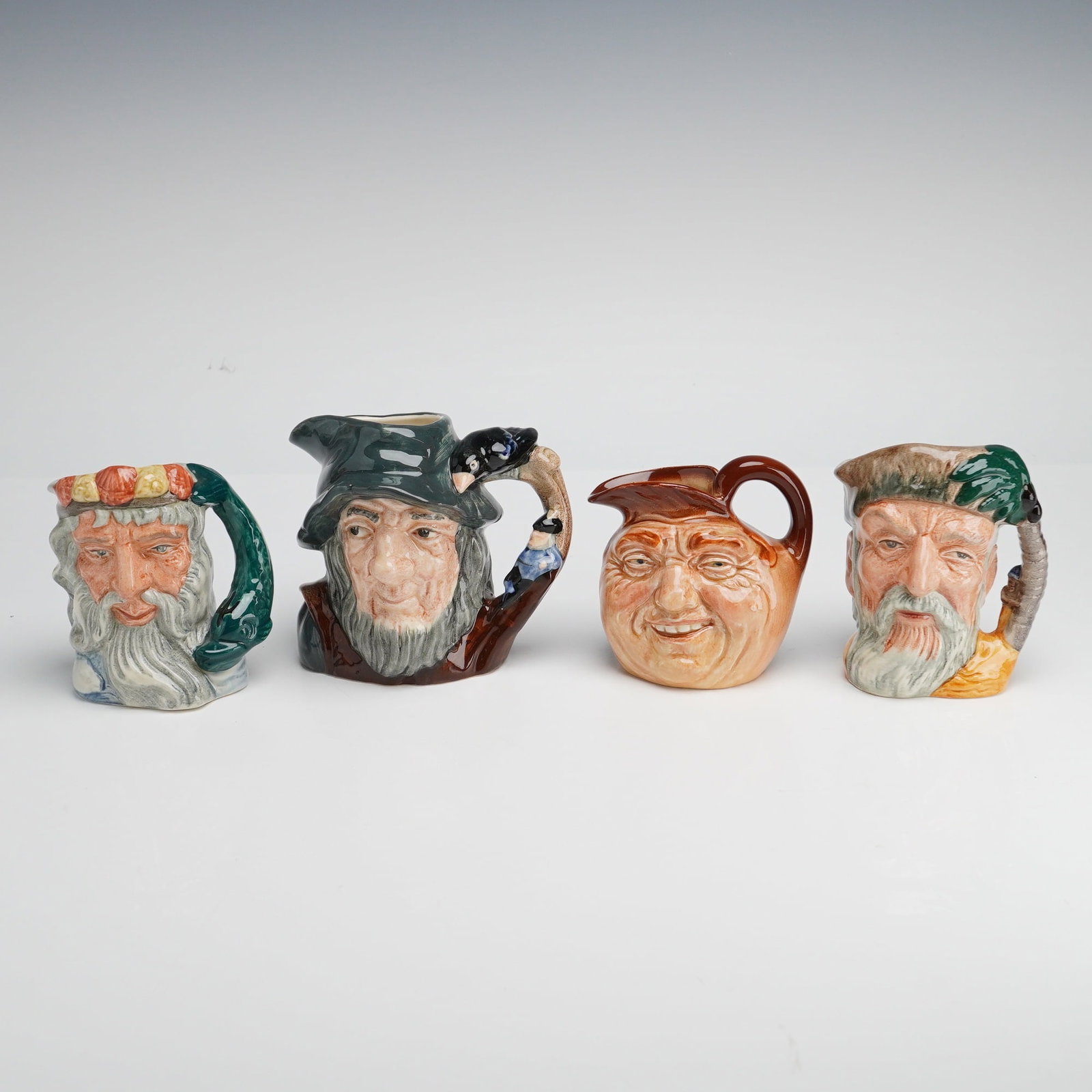 4pc Royal Doulton Character Jugs, Neptune, Rip Van Winkle, John Barleycorn, and Robinson Crusoe: A 4pc collection of Royal Doulton character jugs, crafted in polychrome glazed ceramic. The group features various subjects including Neptune (D6552), Rip Van Winkle (D6463), Robinson Crusoe (D6539), 