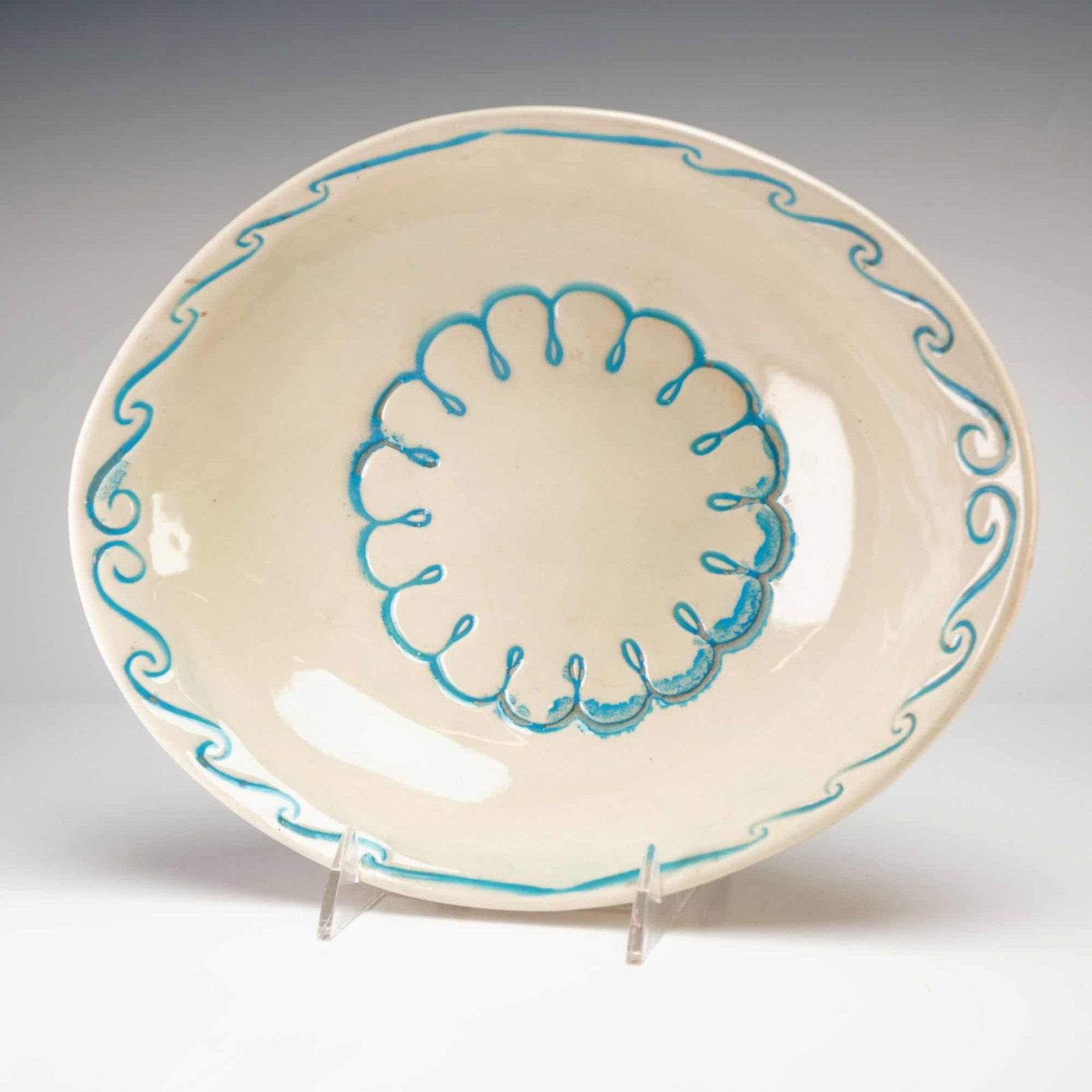 McCoy Decorative White Floral Bowl: McCoy decorative white floral bowl. This glazed ceramic shallow bowl features a cream ground decorated with turquoise blue hand-painted motifs, including a wavy rim border and a central looped