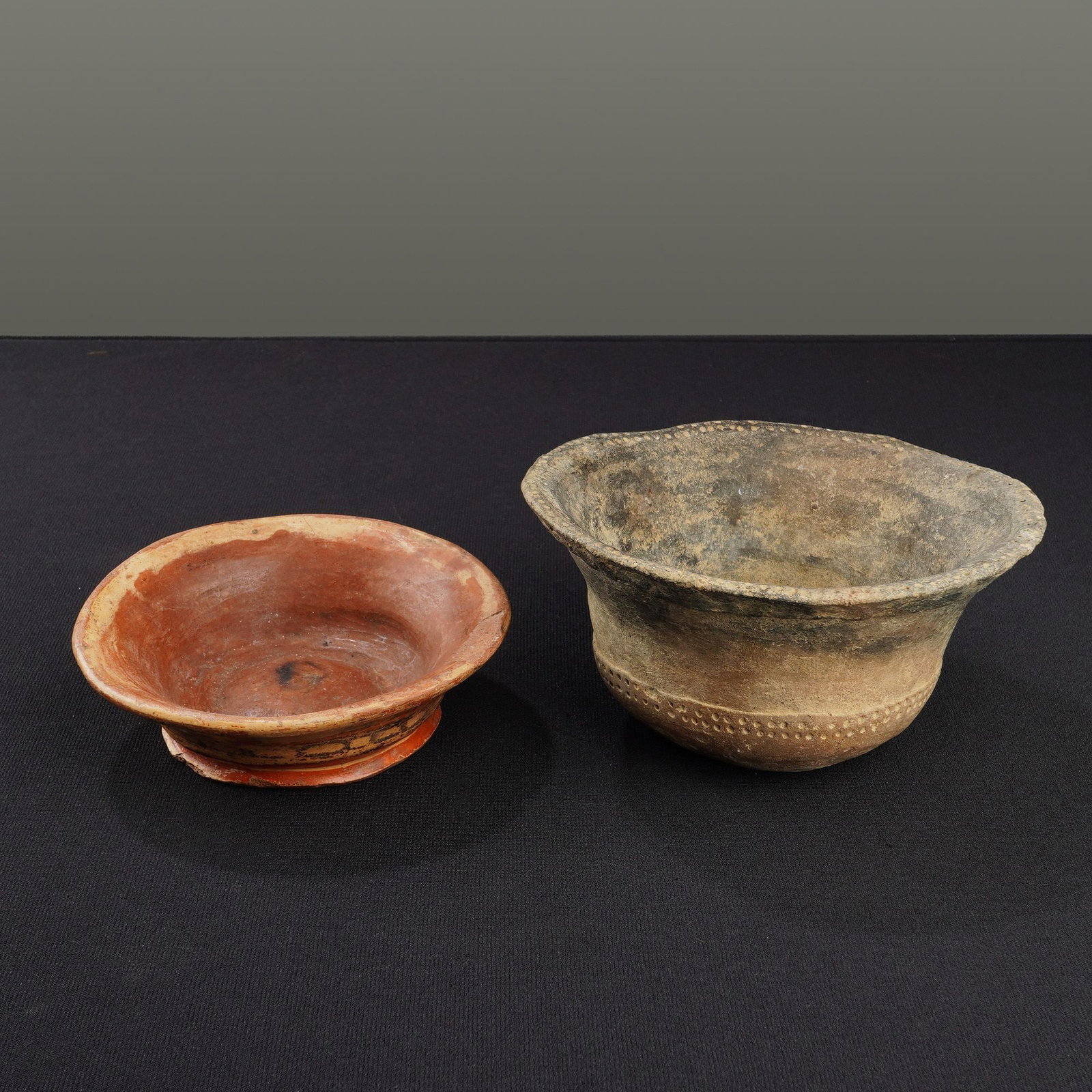 2pc Hand Crafted Ceramic Pottery Bowls: A collection of two hand-formed ceramic vessels of varying styles and sizes. The smaller item is a shallow, footed bowl with a wide, flared rim, featuring polychrome slip-painted geometric patterns
