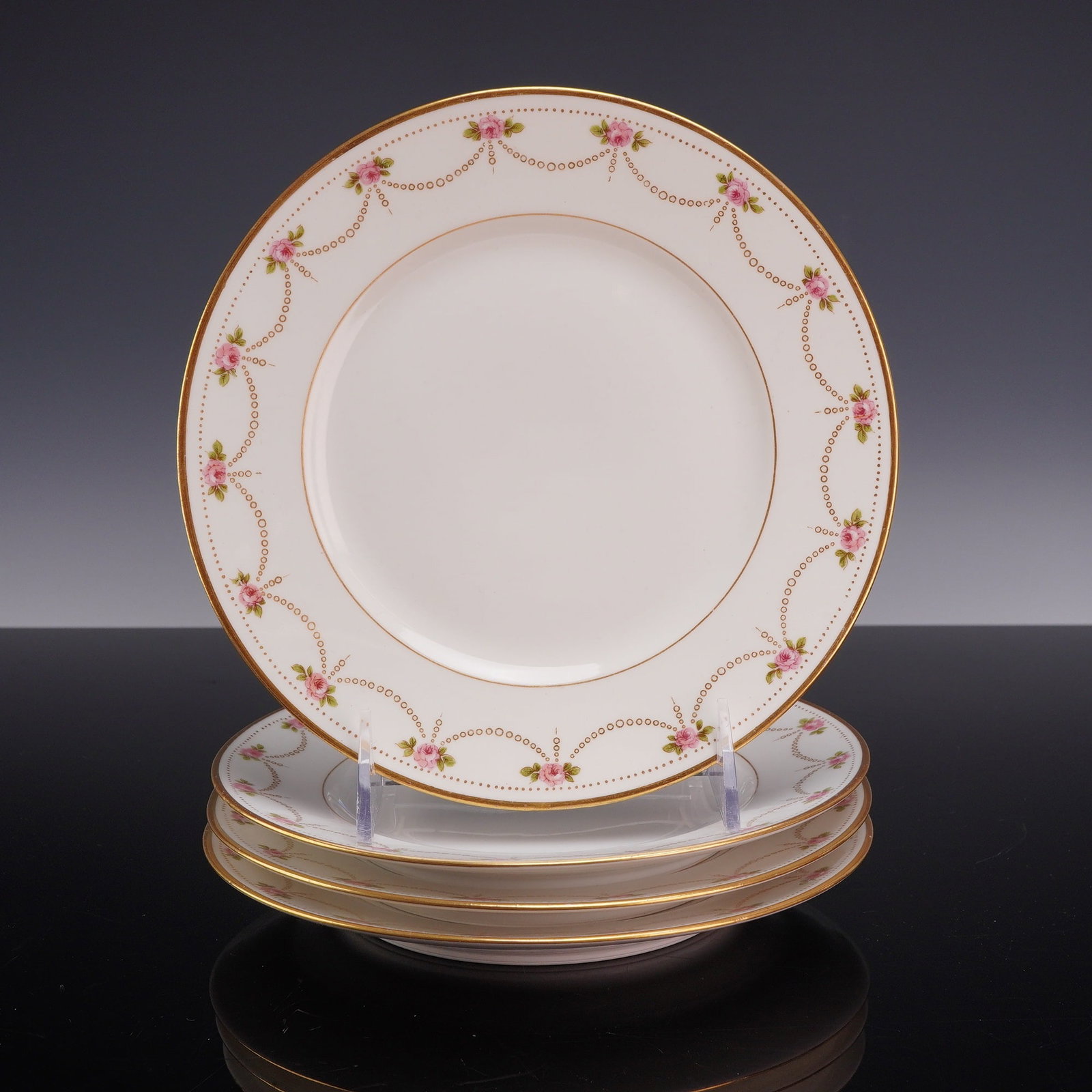 Set of Four Bernardaud and Co Limoges Porcelain Bread and Butter Plates: Set of four porcelain plates manufactured by Bernardaud in Limoges for Henry Morgan and Co., Montreal, Canada. Each circular plate features a gilt edge and a transfer-printed rim decorated with gold-t