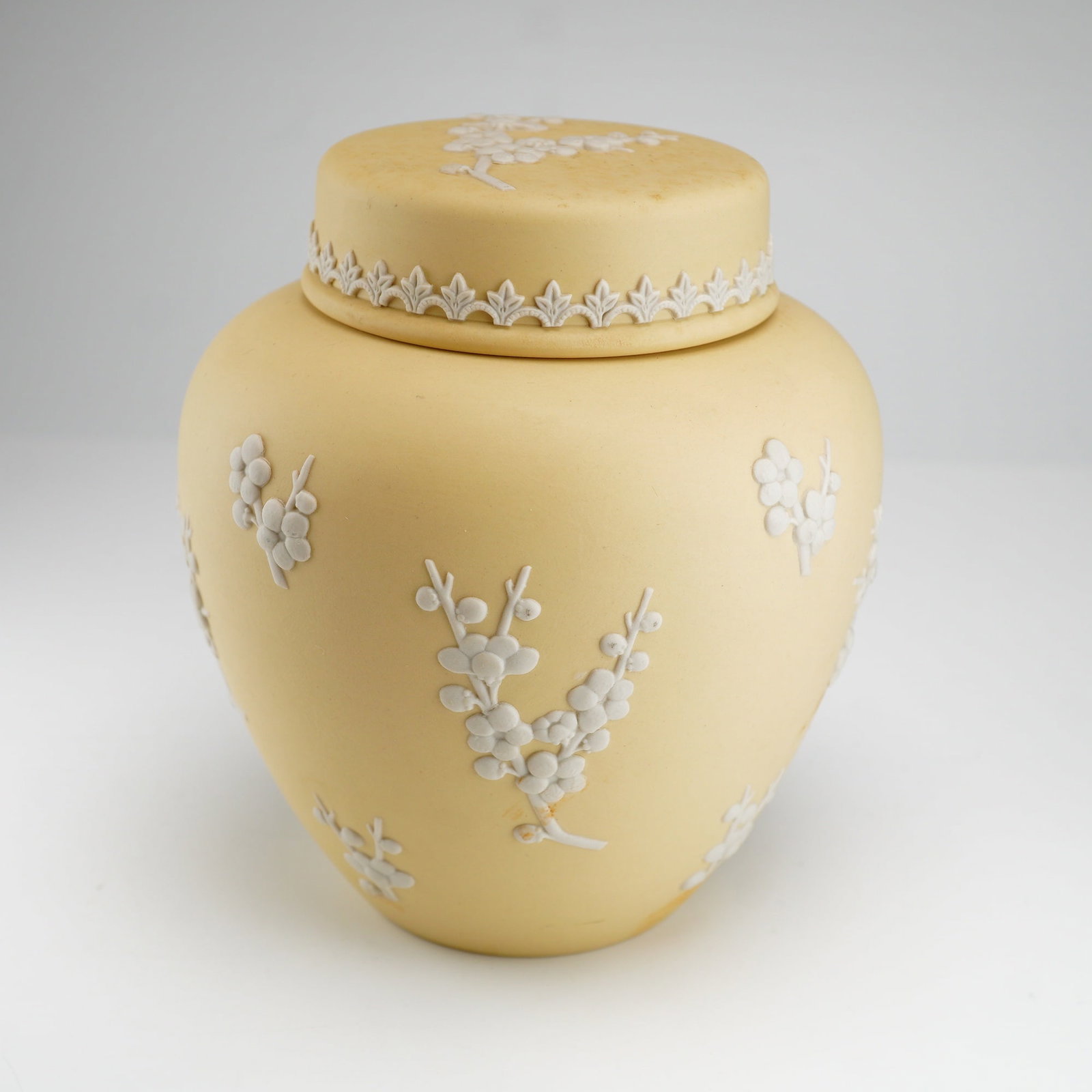 Wedgwood Primrose Jasperware Lidded Ginger Jar: A Wedgwood Jasperware lidded ginger jar of ovoid form with a fitted domed lid. The vessel is crafted from Primrose yellow fine stoneware with a matte finish. The exterior is decorated with white sprig