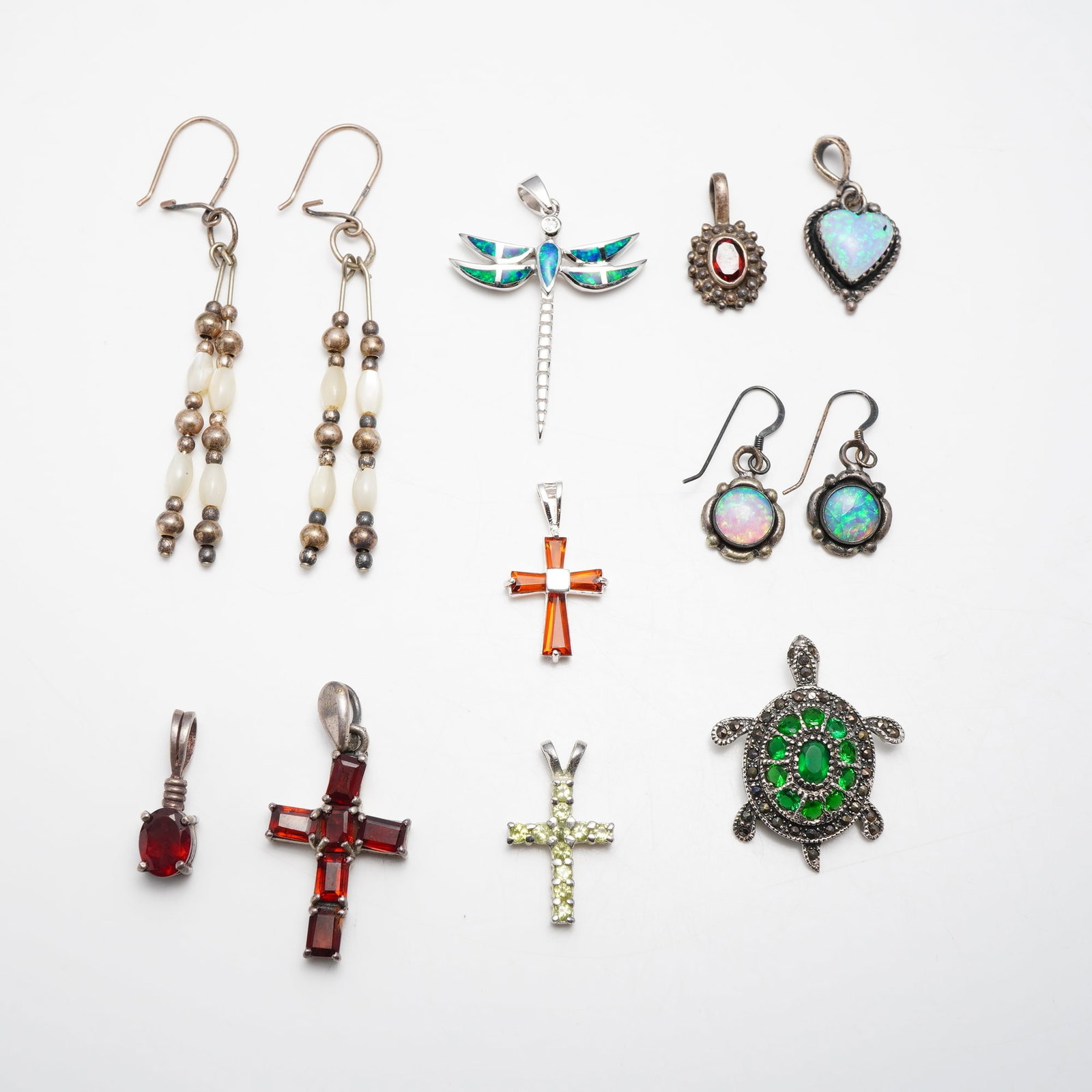 12 Piece Collection of Sterling Silver and Gemstone Jewelry: A twelve piece assortment of jewelry including two pairs of earrings and eight pendants, primarily crafted in sterling silver with various gemstone accents. The collection includes a pair of long dang