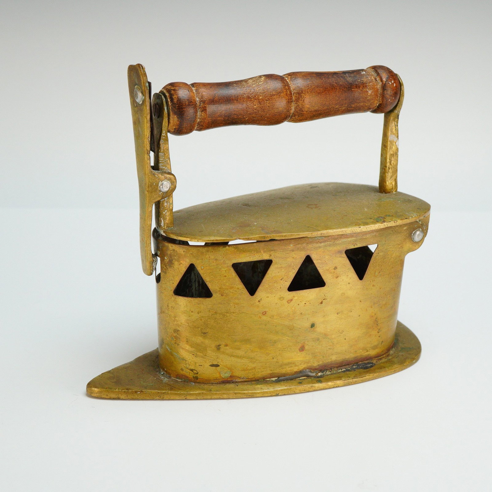 Antique Brass Coal Iron with a Wooden Handle: This antique brass coal iron features a hollow metal body and a turned wooden handle. The design includes a hinged top lid secured by a front latch mechanism to allow for the placement of hot coals wi