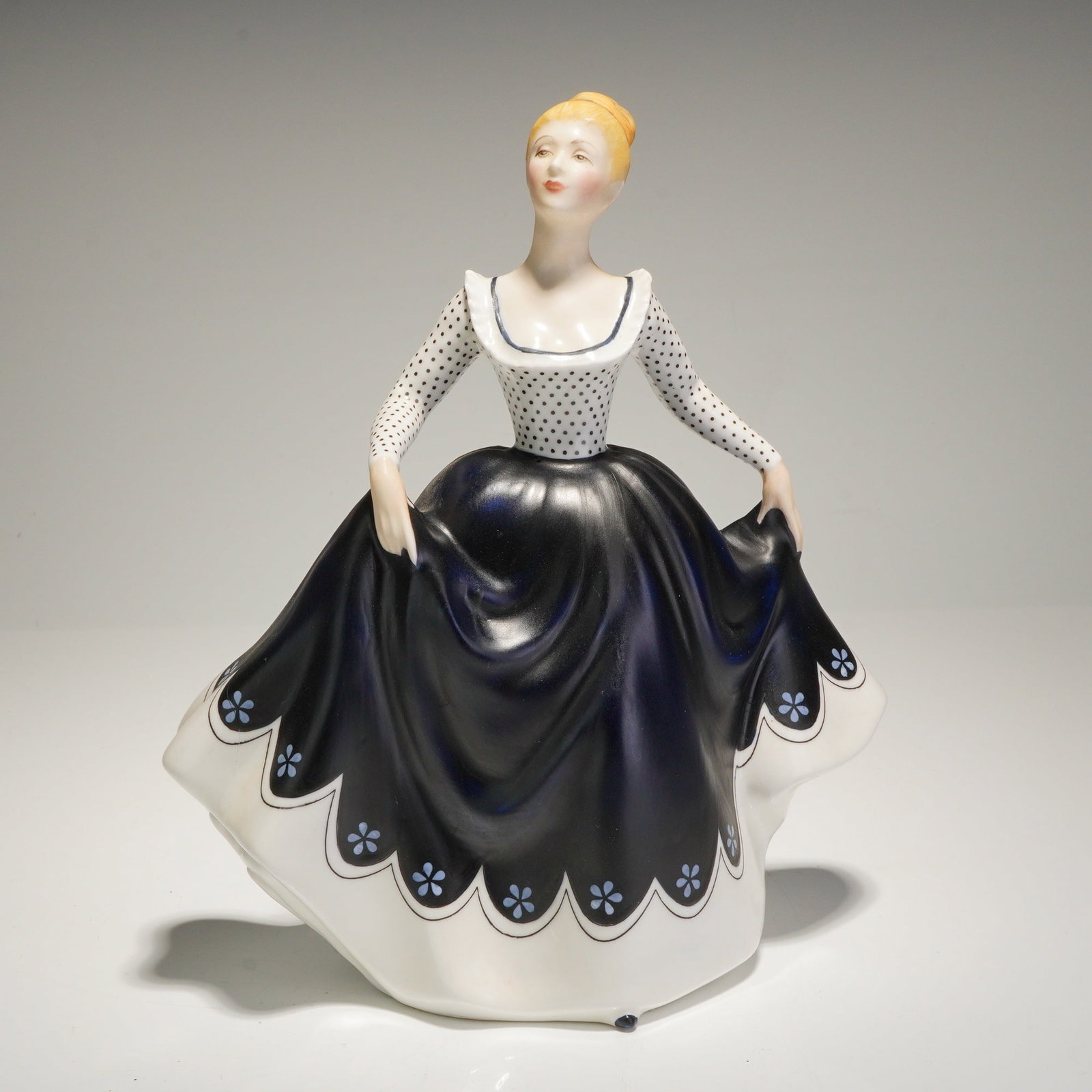 Royal Doulton Figurine Lisa HN2310: A Royal Doulton porcelain figurine titled 'Lisa,' Model Number HN 2310. The figure depicts a woman in a voluminous dress, designed by Peggy Davies. The upper bodice and long sleeves are white with bla