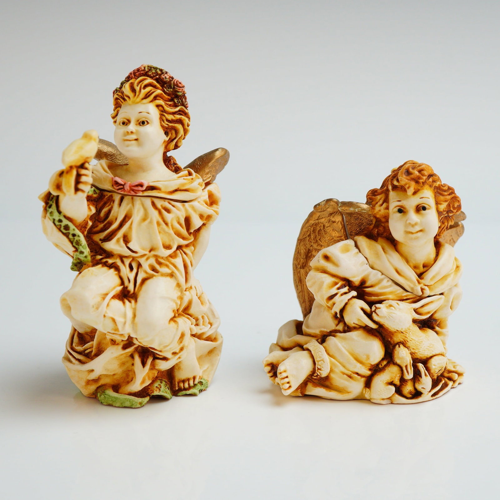 2pc Harmony Kingdom Trinket Boxes, Joie De Vivre and La Gardienne: The box titled La Gardienne (ANSE98) , depicts a winged cherub with a floral crown holding a small bird. The figurine titled Joie De Vivre (ANJO) , depicts a winged cherub holding a rabbit. Both items