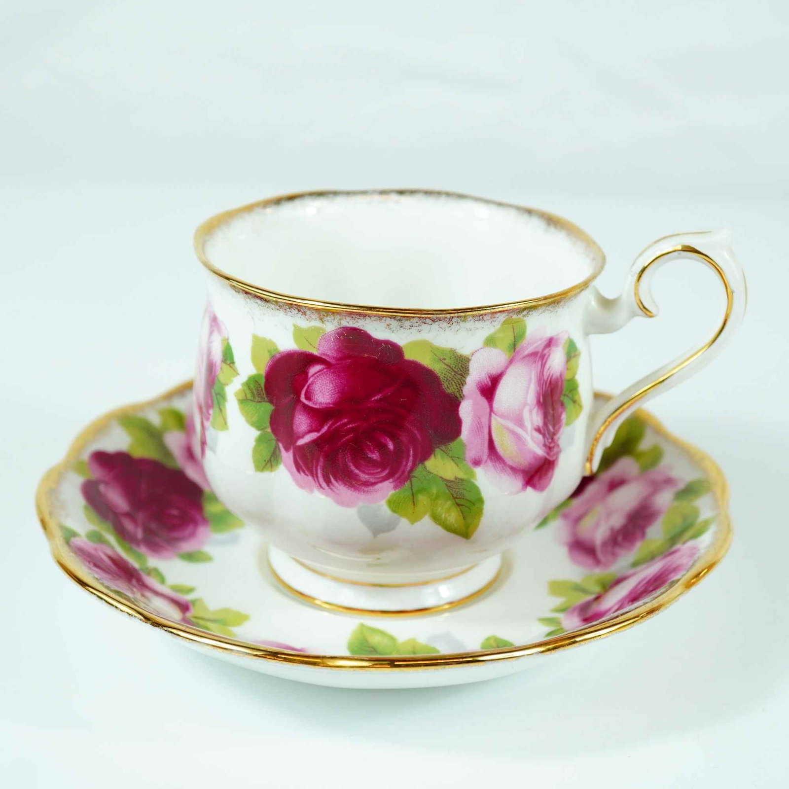 Royal Albert Old English Rose Bone China Teacup and Saucer Set: This two-piece set is manufactured by Royal Albert in the Old English Rose pattern. The set includes a footed teacup in the Montrose shape and a matching saucer with a scalloped, crinkled rim. Both