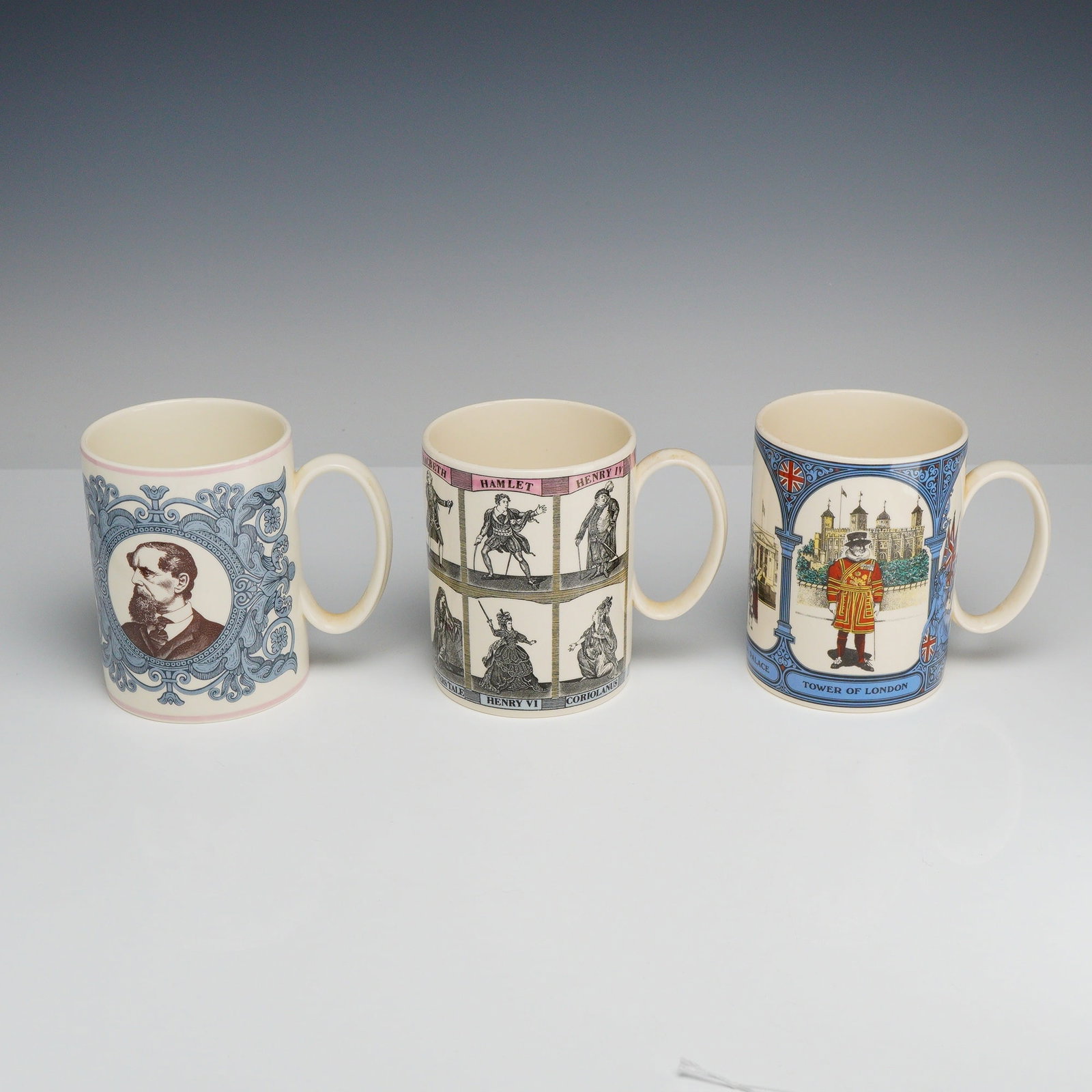 3pc Wedgwood Commemorative Transfer-Printed Earthenware Mugs: This set comprises three commemorative mugs manufactured by Wedgwood in cream-colored earthenware, each featuring multi-color transfer-printed decoration. The first item is The Dickens Centenary Mug,
