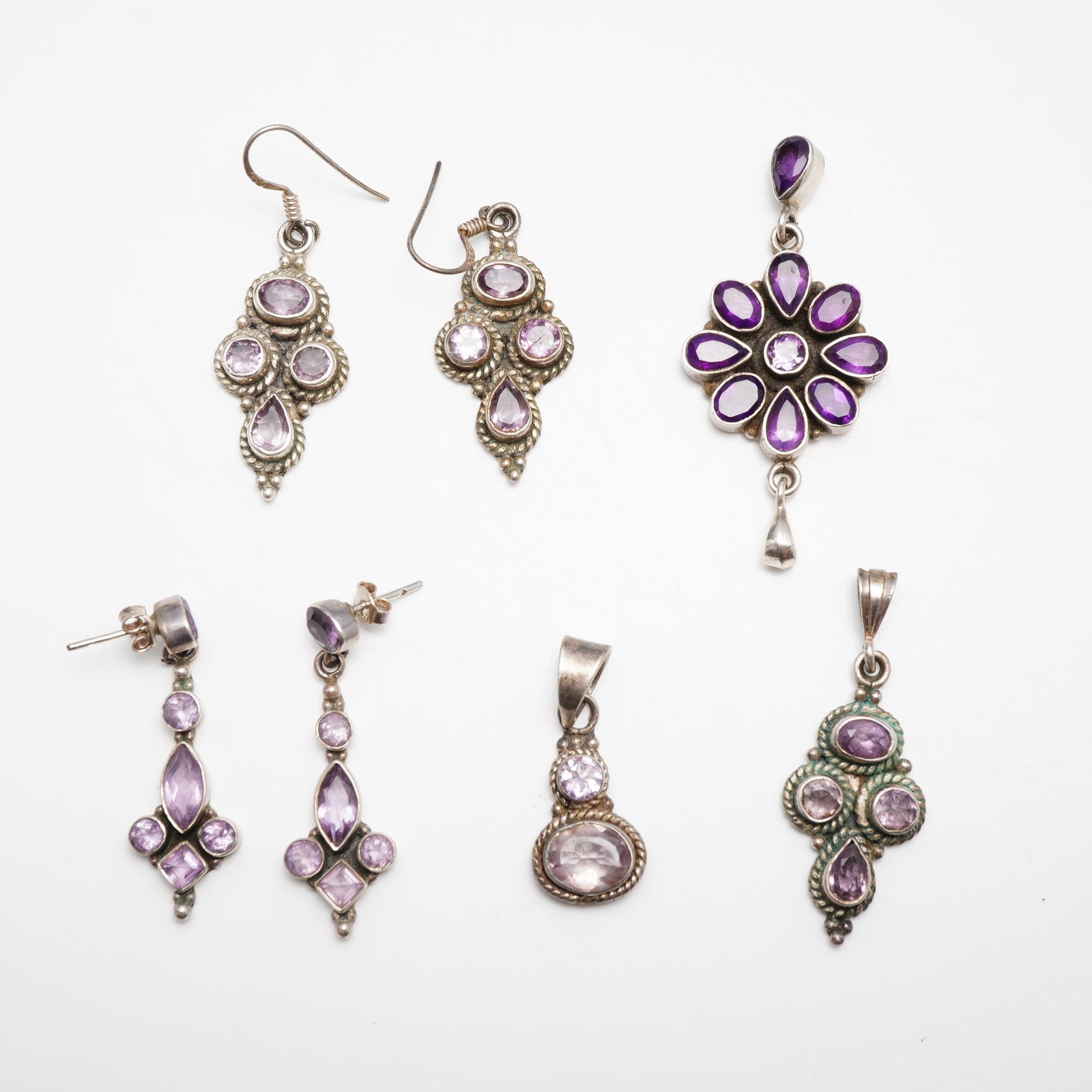 7pc Collection of Sterling Silver and Amethyst Jewelry Including Earrings and Pendants: This lot comprises a 7pc collection of jewelry crafted in sterling silver and set with faceted amethyst gemstones. The group includes two pairs of dangle earrings and three individual pendants. Each p