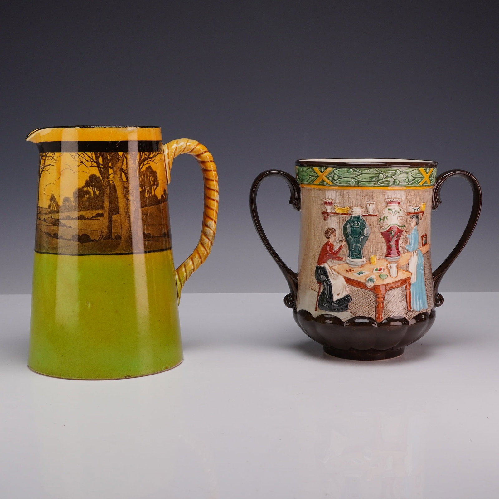 Two Royal Doulton Earthenware Vessels Including a Windmill Landscape Pitcher and a Pottery in the: This lot features two Royal Doulton earthenware vessels from different production periods. The first item is a tapered pitcher decorated in the Windmill Landscape pattern (D2538), also known as Woodle