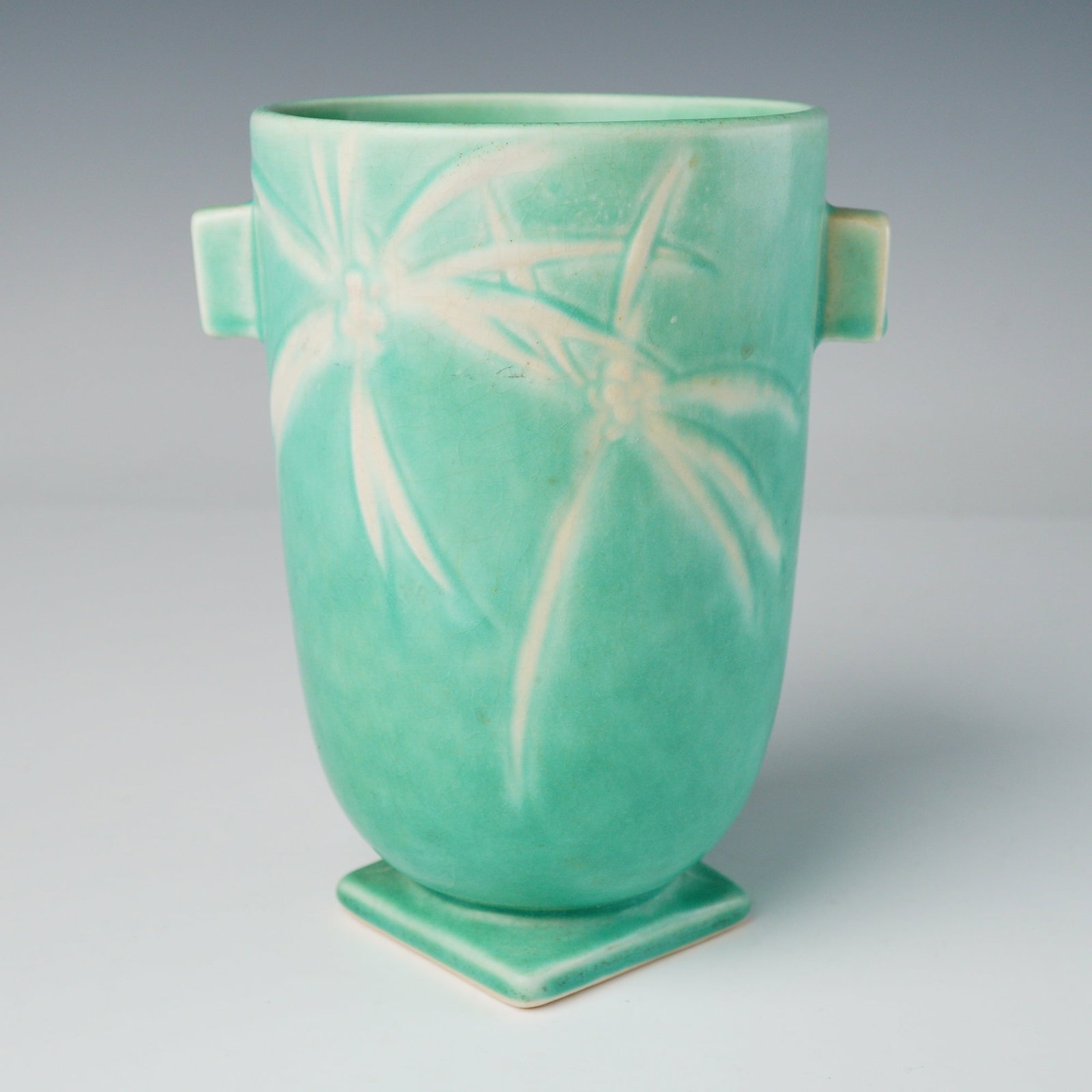 Roseville Pottery Dawn Pattern Art Deco Ceramic Vase: A single ceramic Art Deco vase attributed to Roseville Pottery, executed in the Dawn pattern (introduced circa 1937). The vessel features a gently tapering cylindrical body resting upon a square pedes