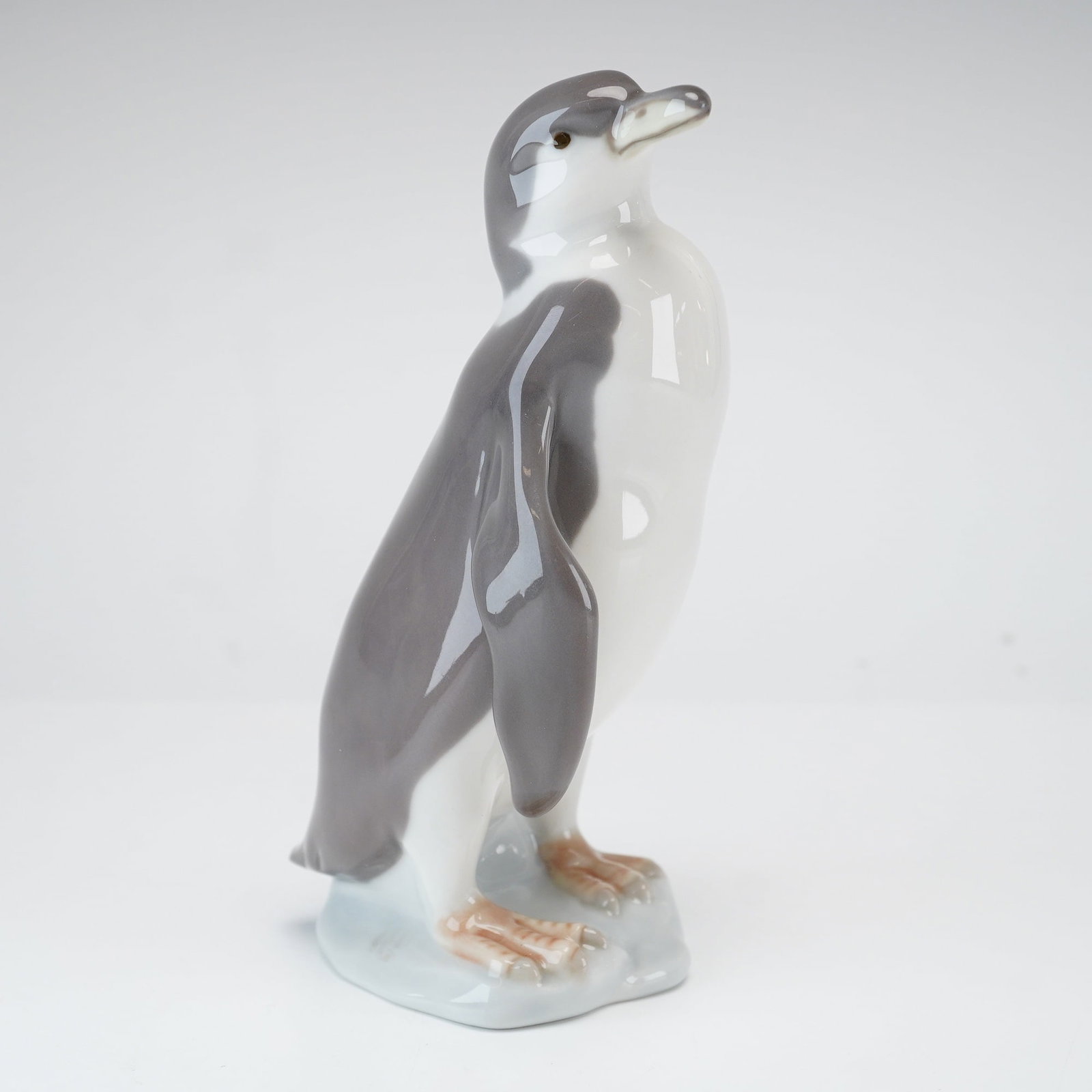 Lladro Porcelain Figurine, Penguin 01005249: A Lladro glazed porcelain figurine titled Penguin, model number 5249. Designed by sculptor Fulgencio Garcia and issued starting in 1984, the figurine depicts a standing penguin with its head turned to