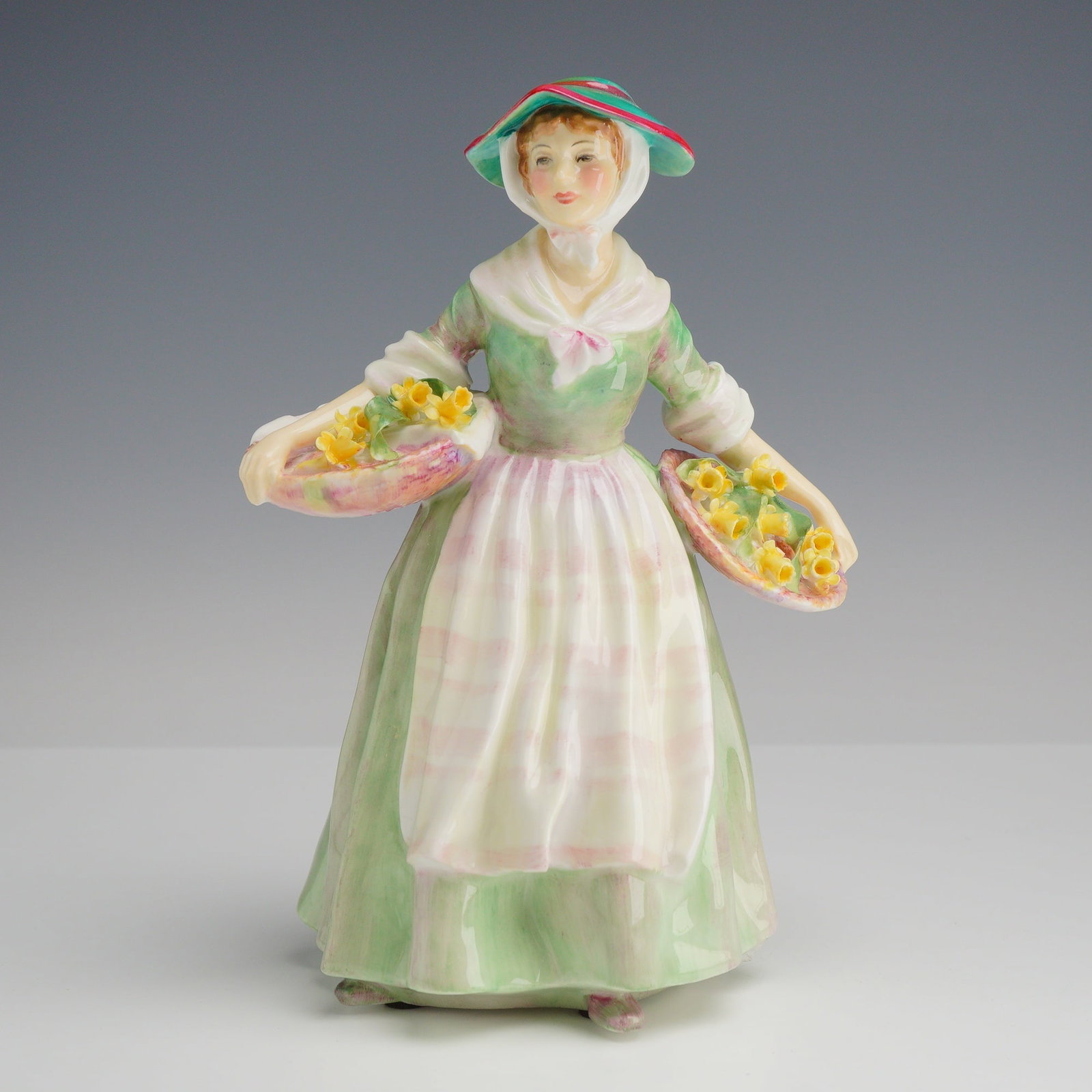 Royal Doulton Porcelain Figurine Daffy-Down-Dilly HN 1712: This polychrome glazed bone china figurine, titled Daffy-Down-Dilly, is produced by Royal Doulton. The piece depicts a young woman in stylized 18th-century country attire, featuring a full-length pale