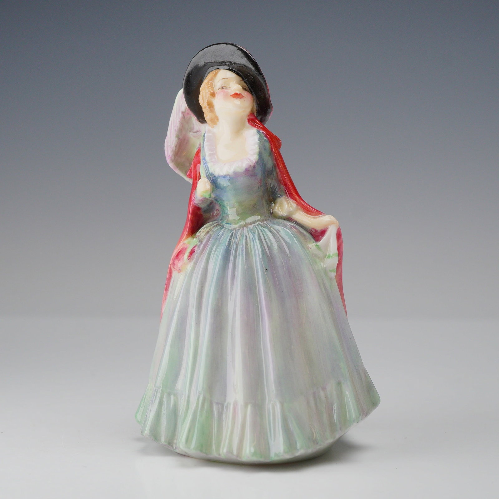 Royal Doulton Porcelain Figurine, Mirabel M74: This Royal Doulton bone china figurine, titled Mirabel, number M74, depicts a woman in 18th-century style attire. The figure is posed standing in a voluminous gown decorated with an iridescent glaze f
