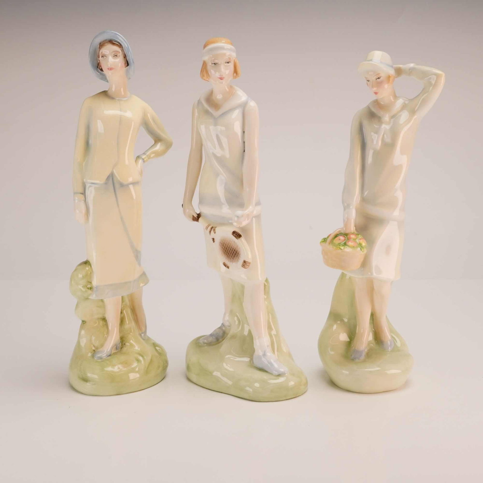 Lot of Three Royal Doulton Bone China Figurines, Ellen HN3816, Emily HN3807, and Sophie HN3791: A lot of three Royal Doulton glazed bone china figurines, each depicting a woman in 1920s-style attire. The collection includes the models Sophie (HN 3791), Emily (HN 3807), and Ellen (HN 3815), all m