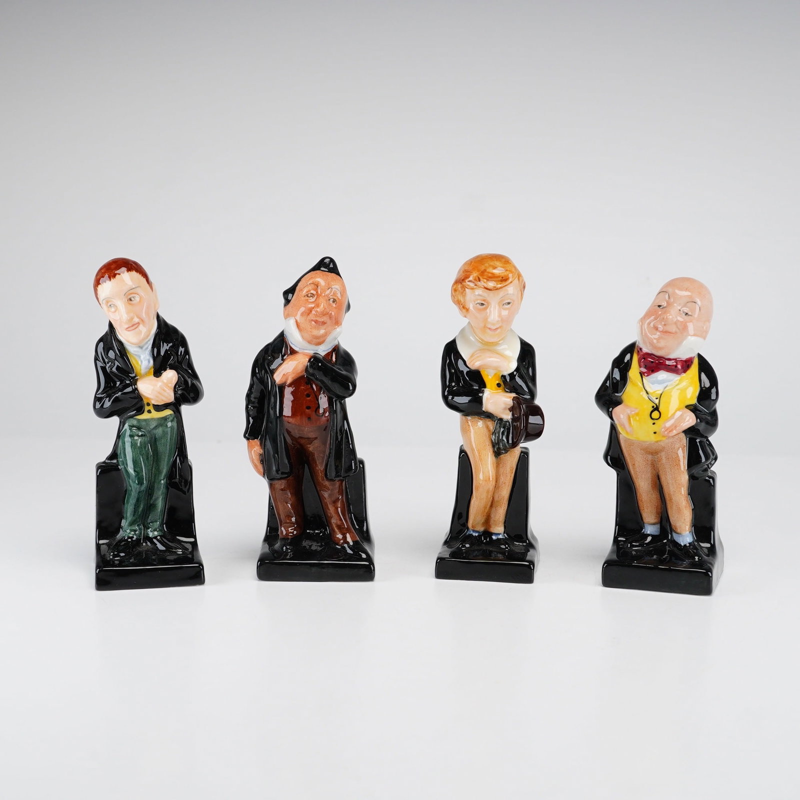 4pc Royal Doulton Miniature Dickens Figurines: This set of 4pc Royal Doulton miniature figurines features characters from the literature of Charles Dickens. Each figure is crafted from glazed bone china and exhibits hand-painted details. The set i