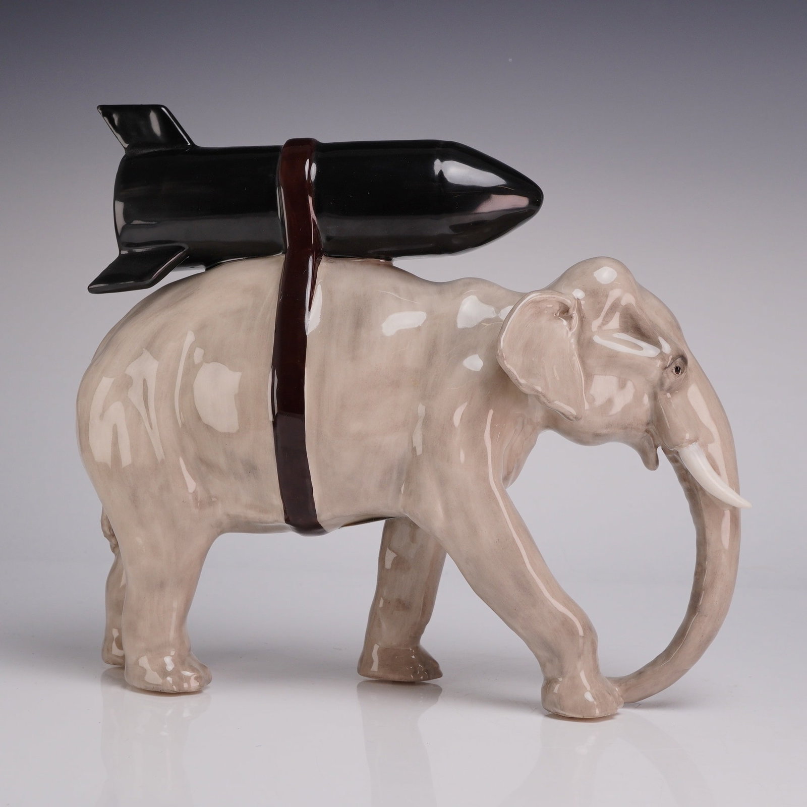 Kevin Francis Street Art Heavy Weaponry Limited Edition Ceramic Elephant Figurine: This glazed ceramic figurine is part of the Kevin Francis Street Art series and is titled Heavy Weaponry. The sculpture depicts a walking elephant finished in a high-gloss gray glaze. A large, glossy 