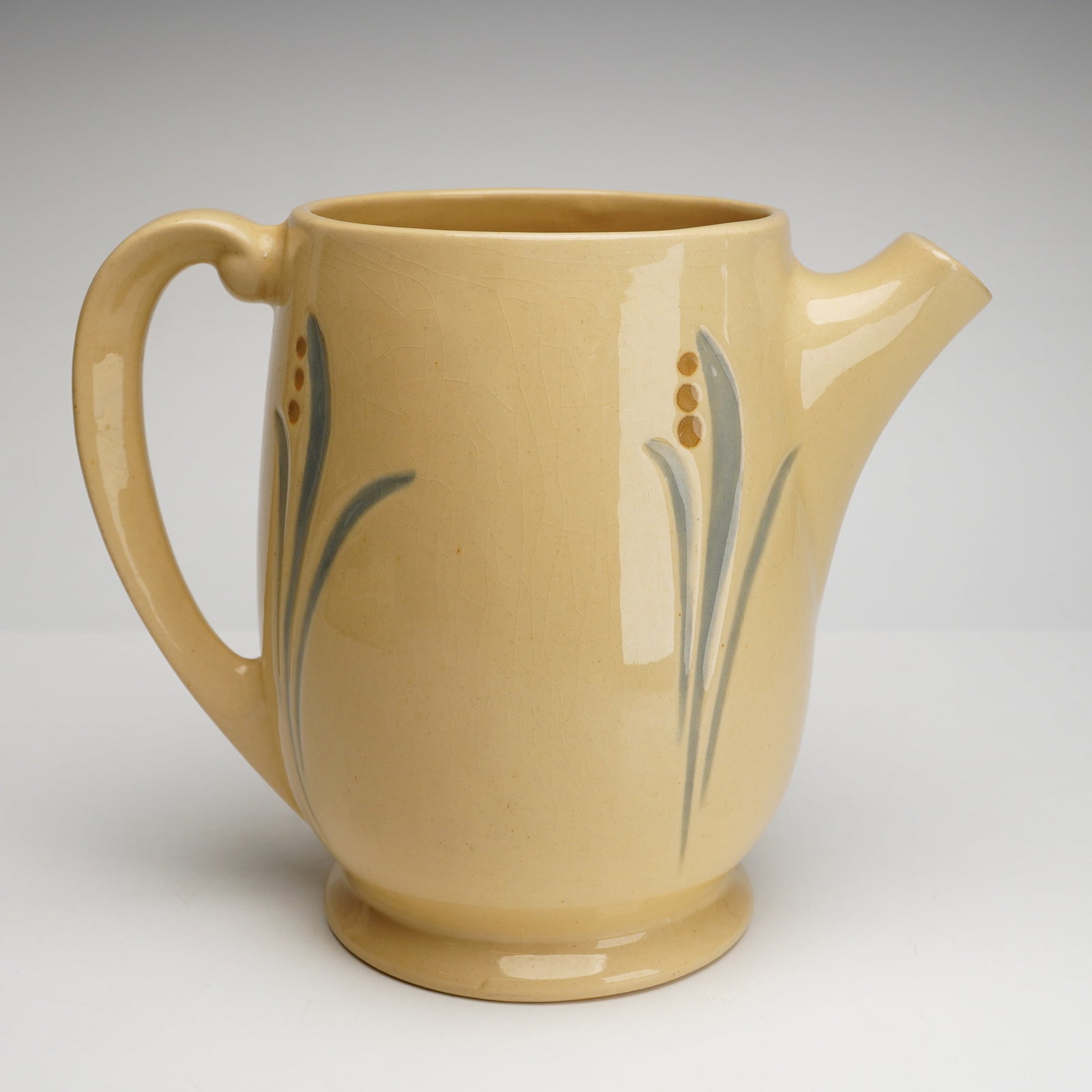 Roseville Pottery Pitcher, Lilies of the Valley: An early 20th-century Art Deco style ceramic pitcher produced by Roseville Pottery as part of their Utility line, featuring the Lilies of the Valley pattern. The earthenware vessel is finished in a pa
