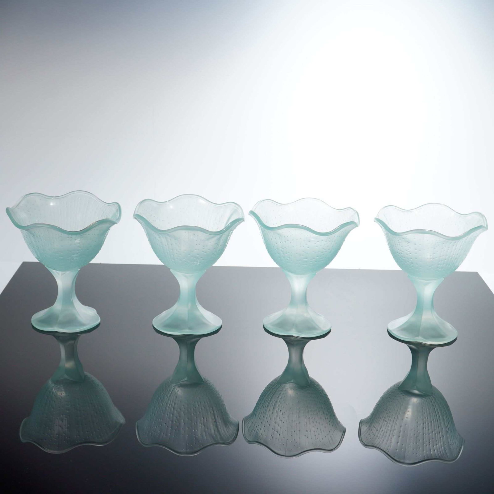 4pc French Frosted Seafoam Blue Glass Footed Dessert Bowls: This set of four glass dessert bowls is constructed from frosted satin glass in a pale seafoam blue color. Each bowl features a flared, scalloped rim and a molded exterior pattern characterized by ver
